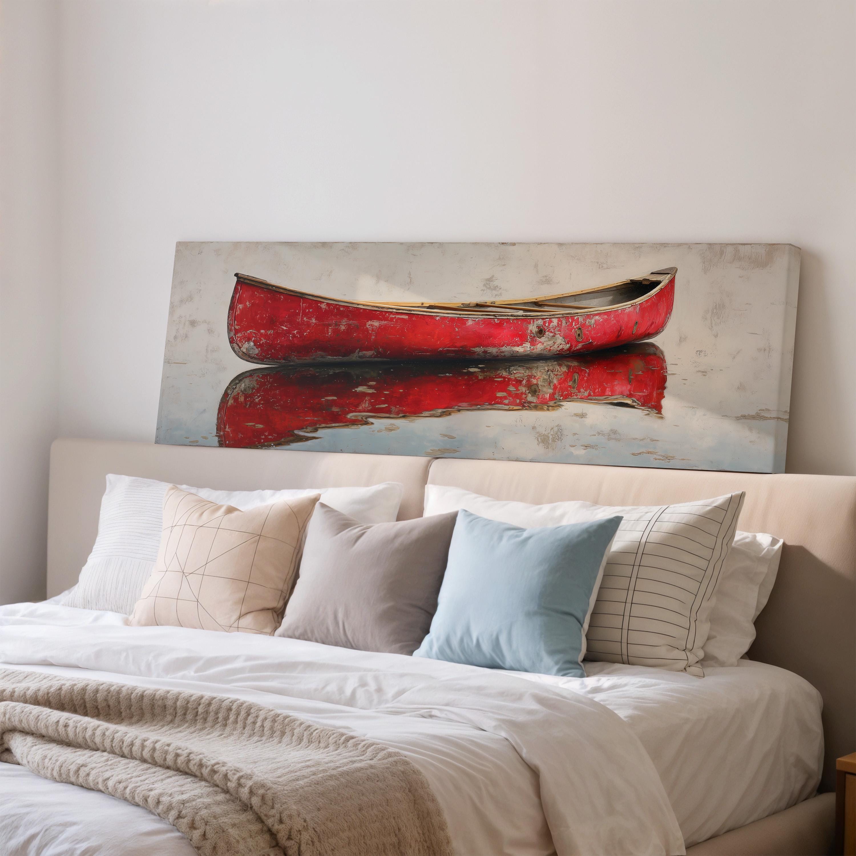 a large canvas print of a red canoe on a white wall above a bed with white bedding and pillows.