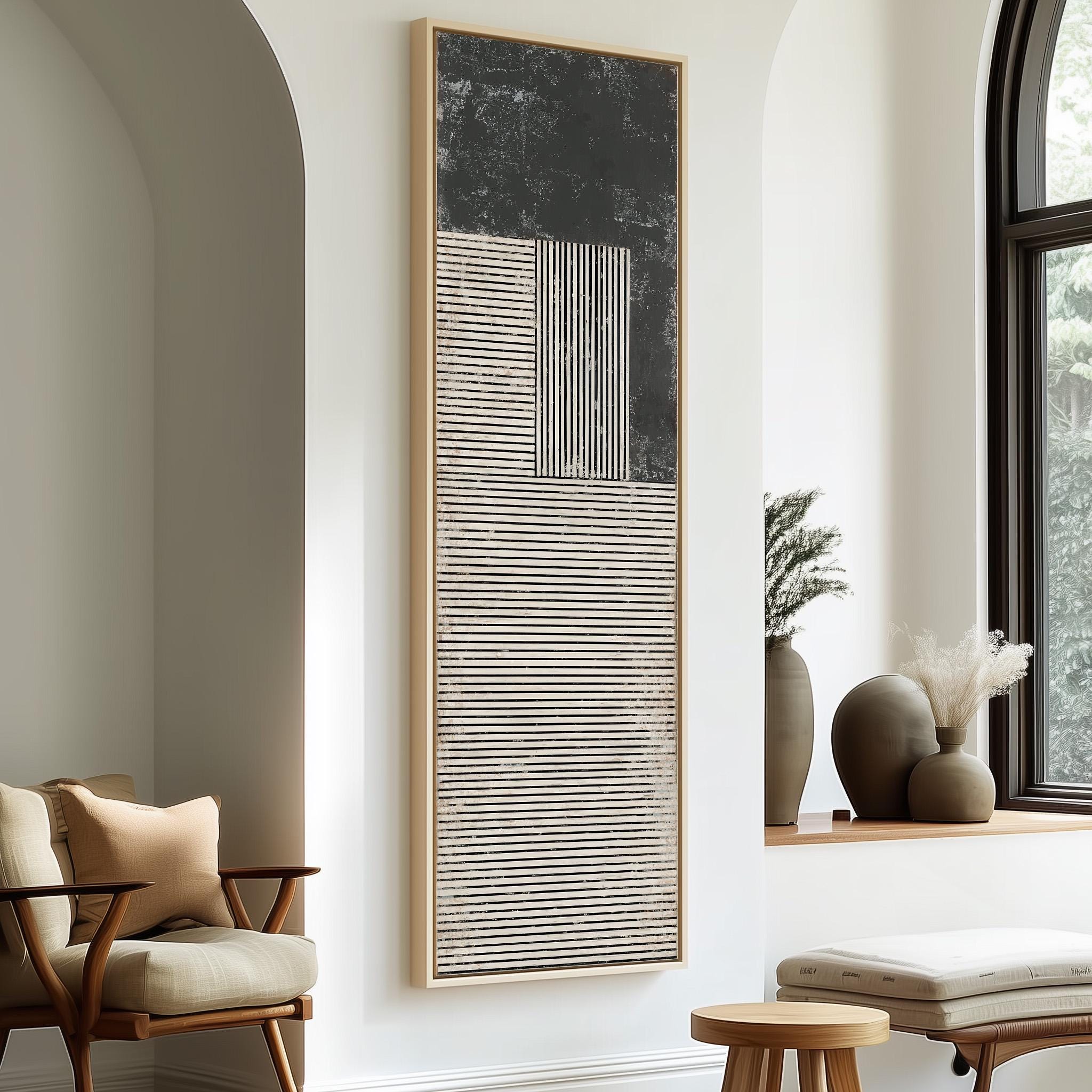 a modern and minimalist living room with a large abstract painting on the wall, a wooden chair, a small table, and a window with a plant on the sill.