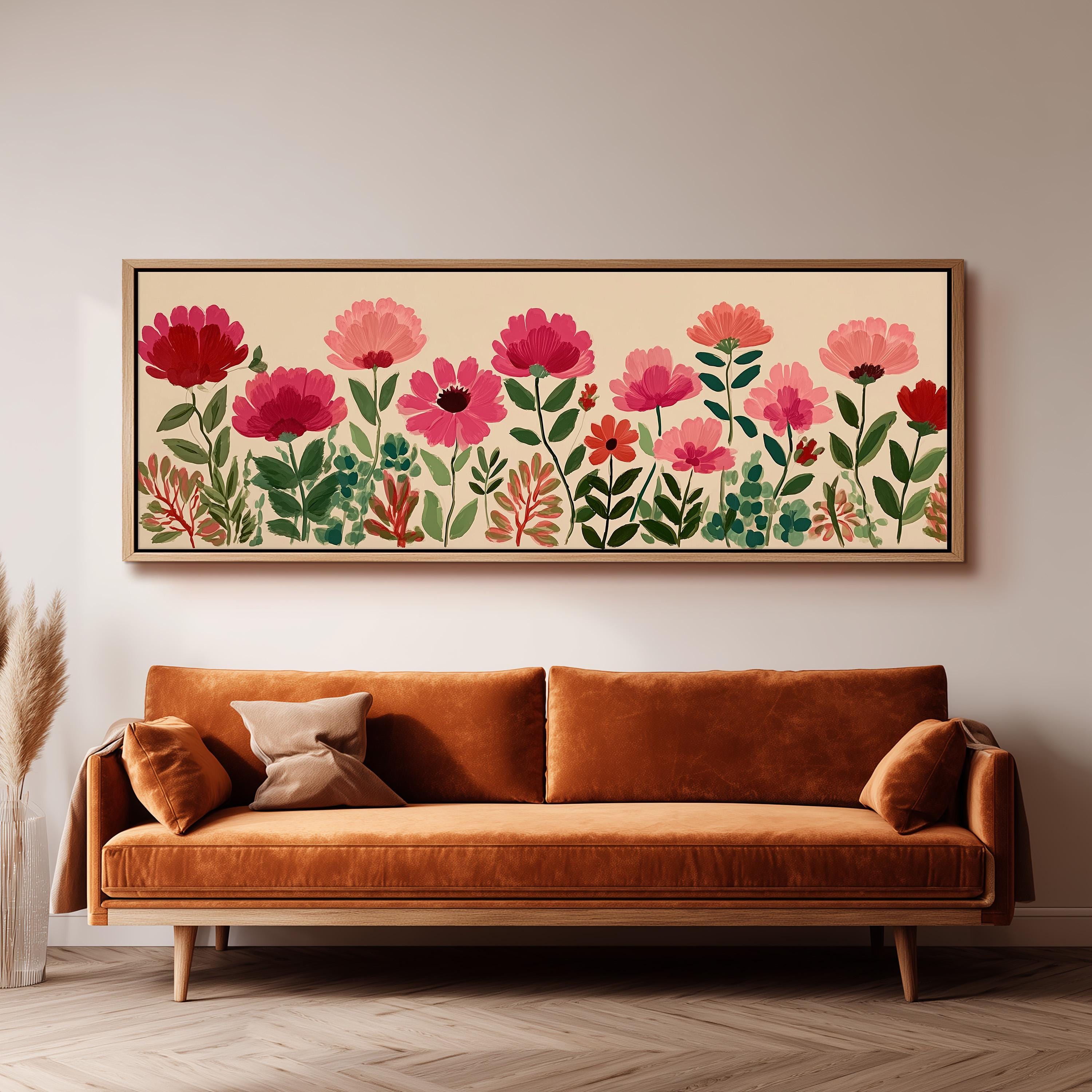 a large, framed print of a floral design hanging on a wall above a brown sofa.