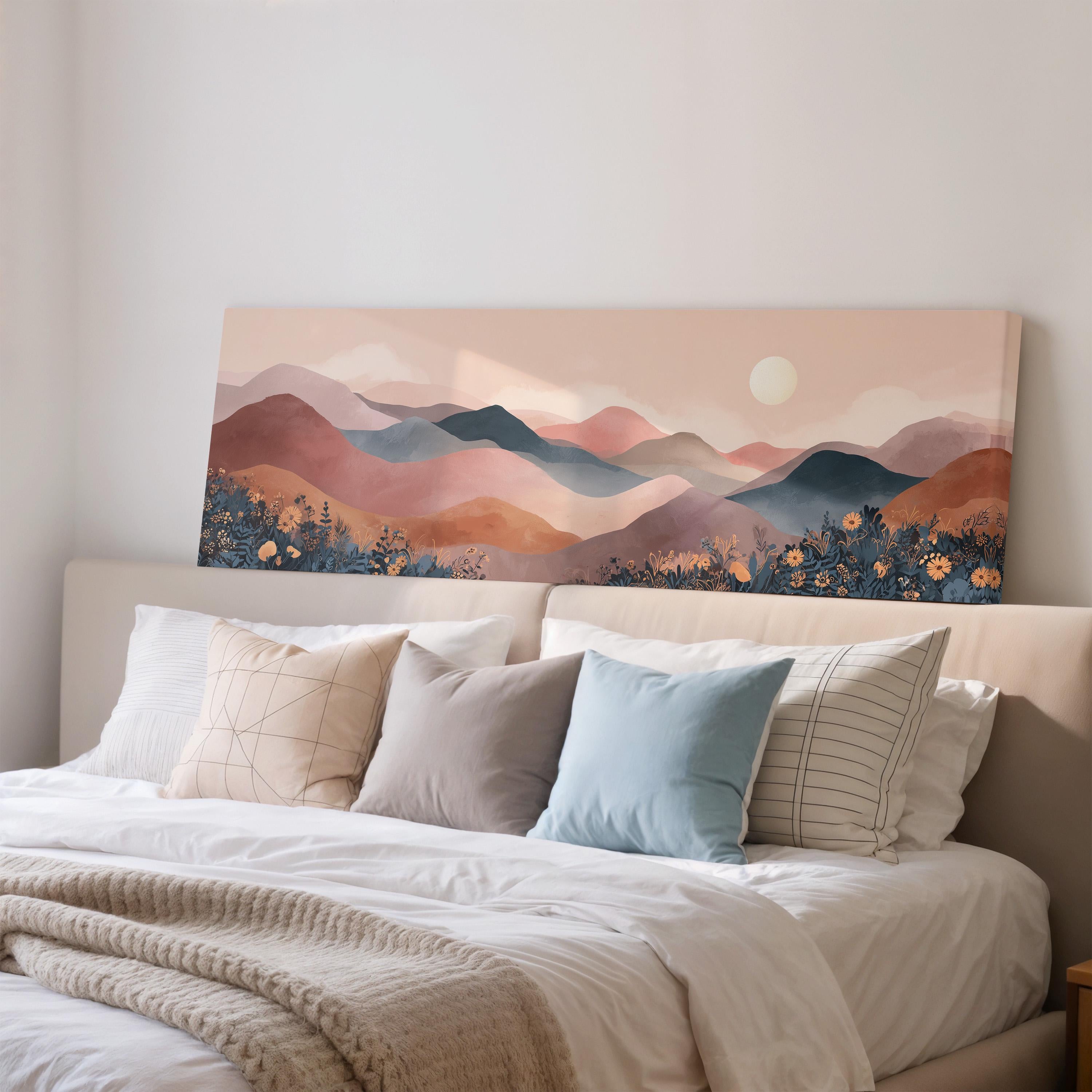 a large canvas print of a mountain landscape with a sunset over the mountains, hanging above a bed with white pillows and a gray blanket.