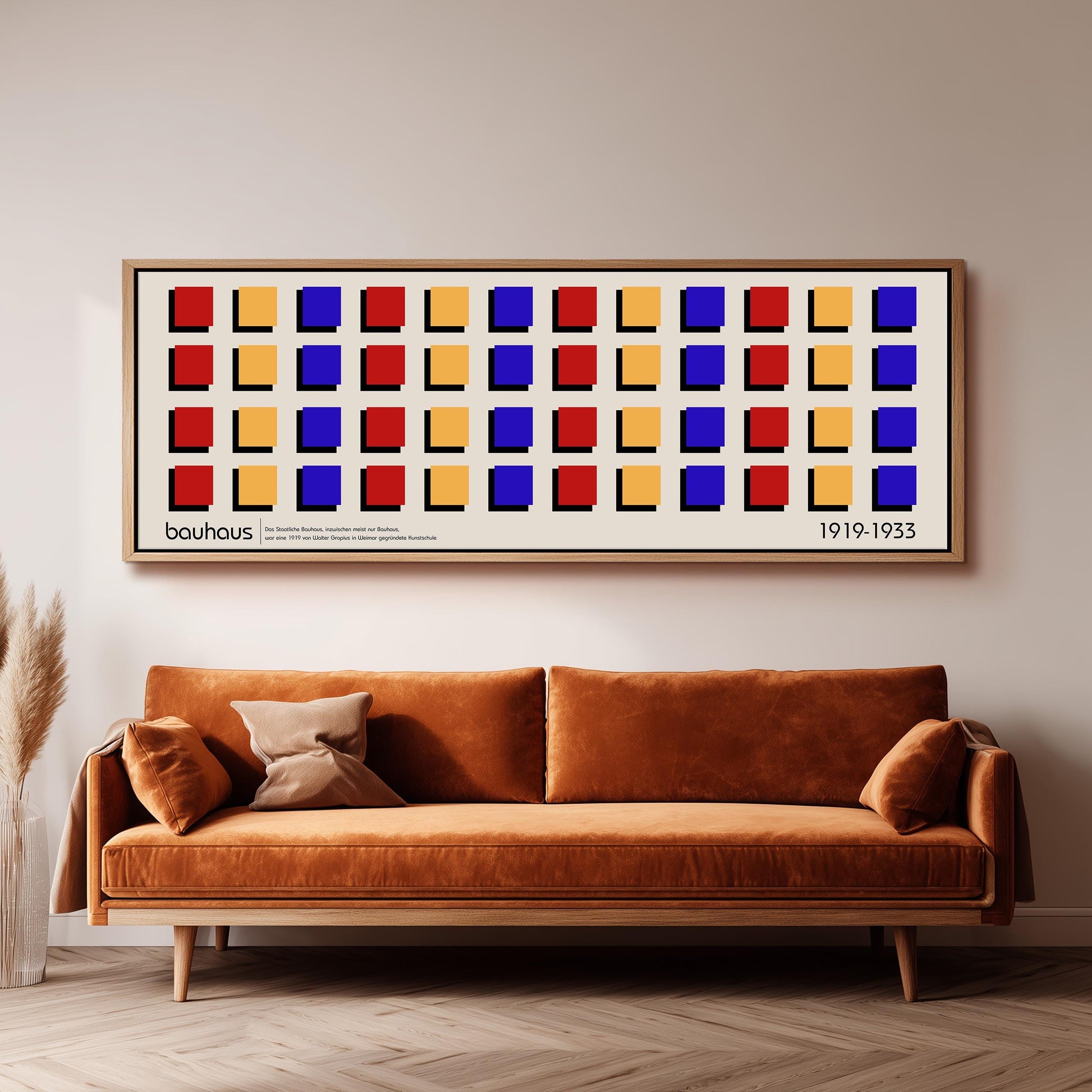 a large, rectangular framed poster with a repeating pattern of squares in various colors, including red, yellow, blue, and orange, hanging on a wall above a brown sofa.