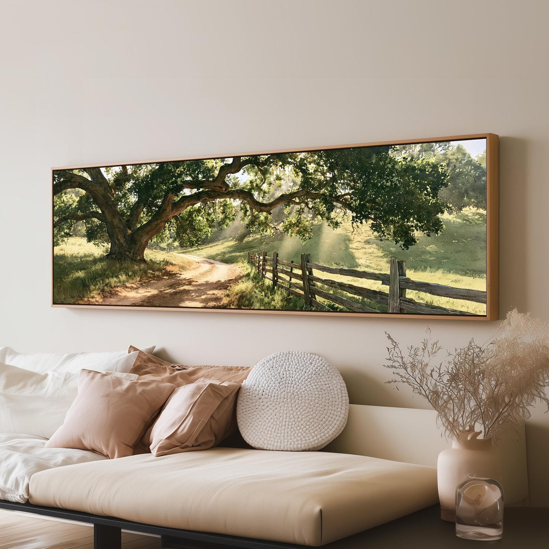 Sunlit country lane with oak trees and a wooden fence long horizontal canvas print above a sofa in a living room