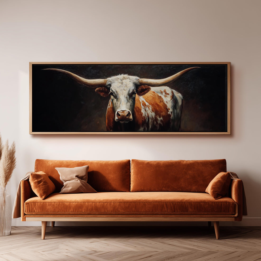 a large painting of a bull with long horns hanging on a wall above a brown sofa.