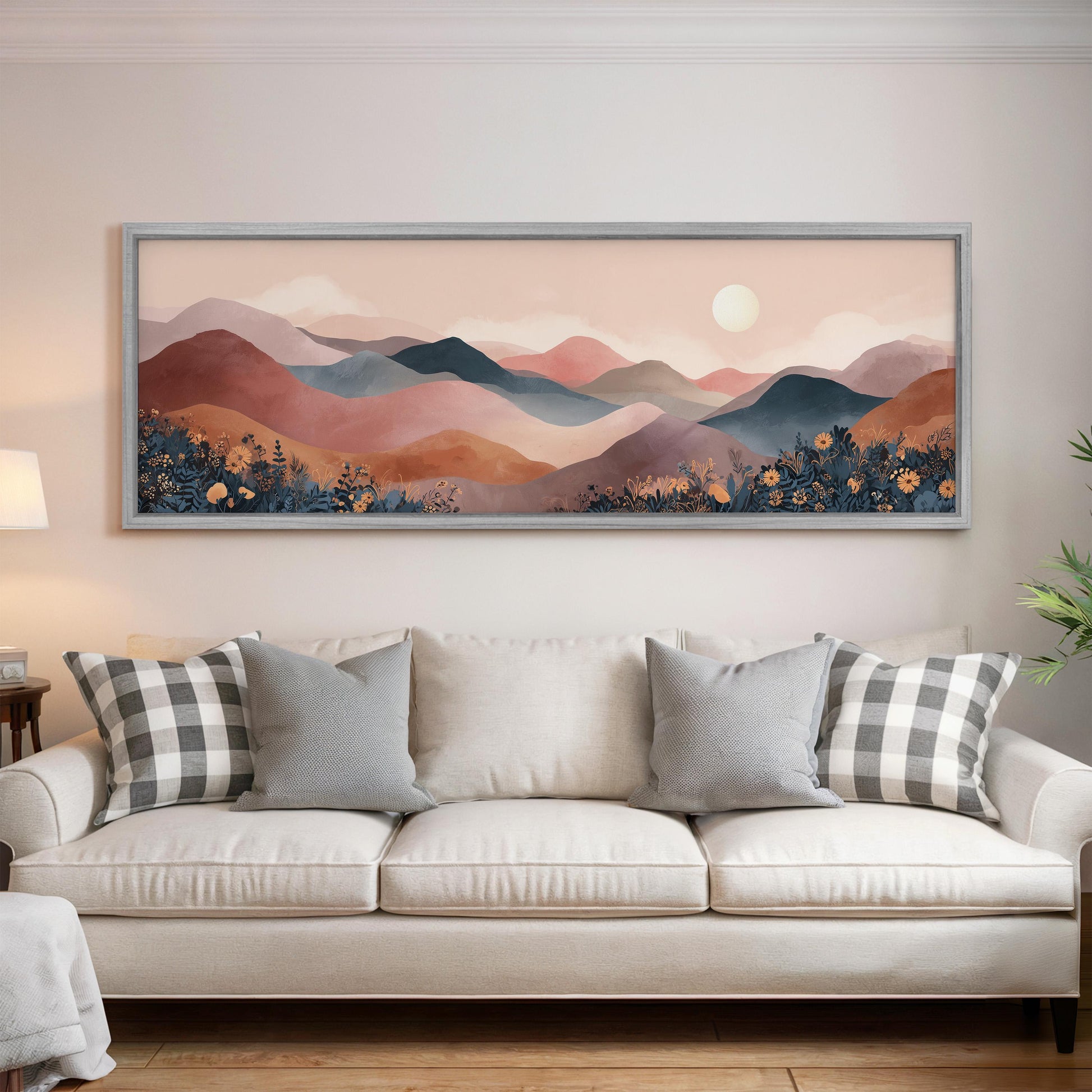 a large framed painting of a mountain landscape hanging on a wall above a white sofa with patterned throw pillows.