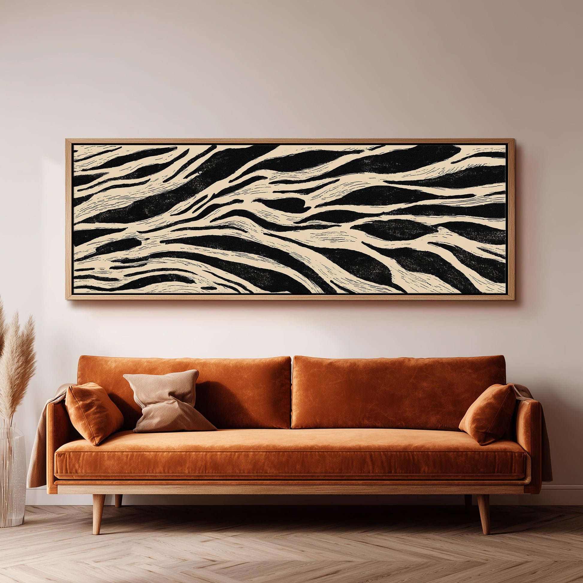 a large, rectangular black and white abstract painting hanging on a white wall above a brown sofa with orange cushions.