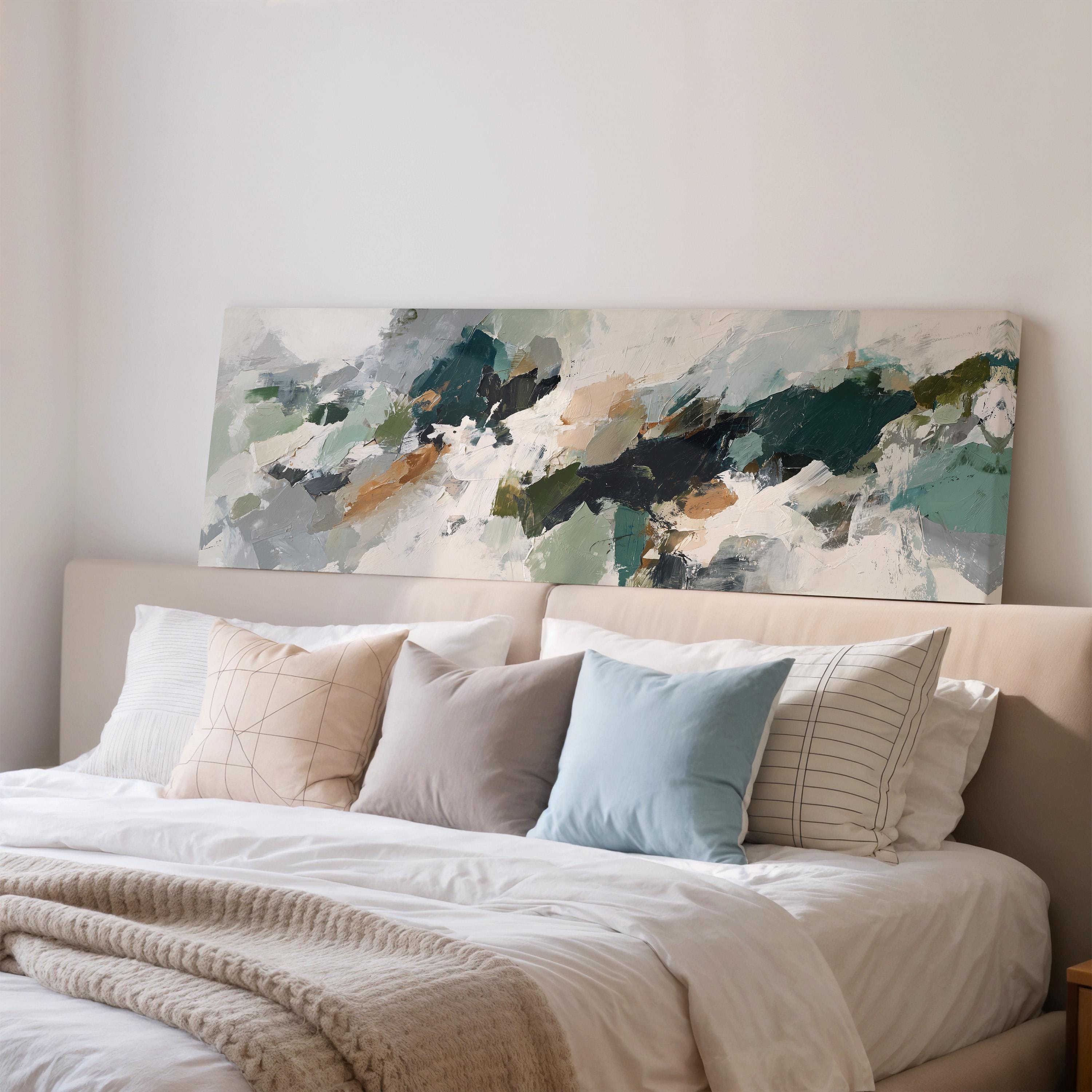 a large abstract painting hanging above a bed with white pillows and a gray blanket.