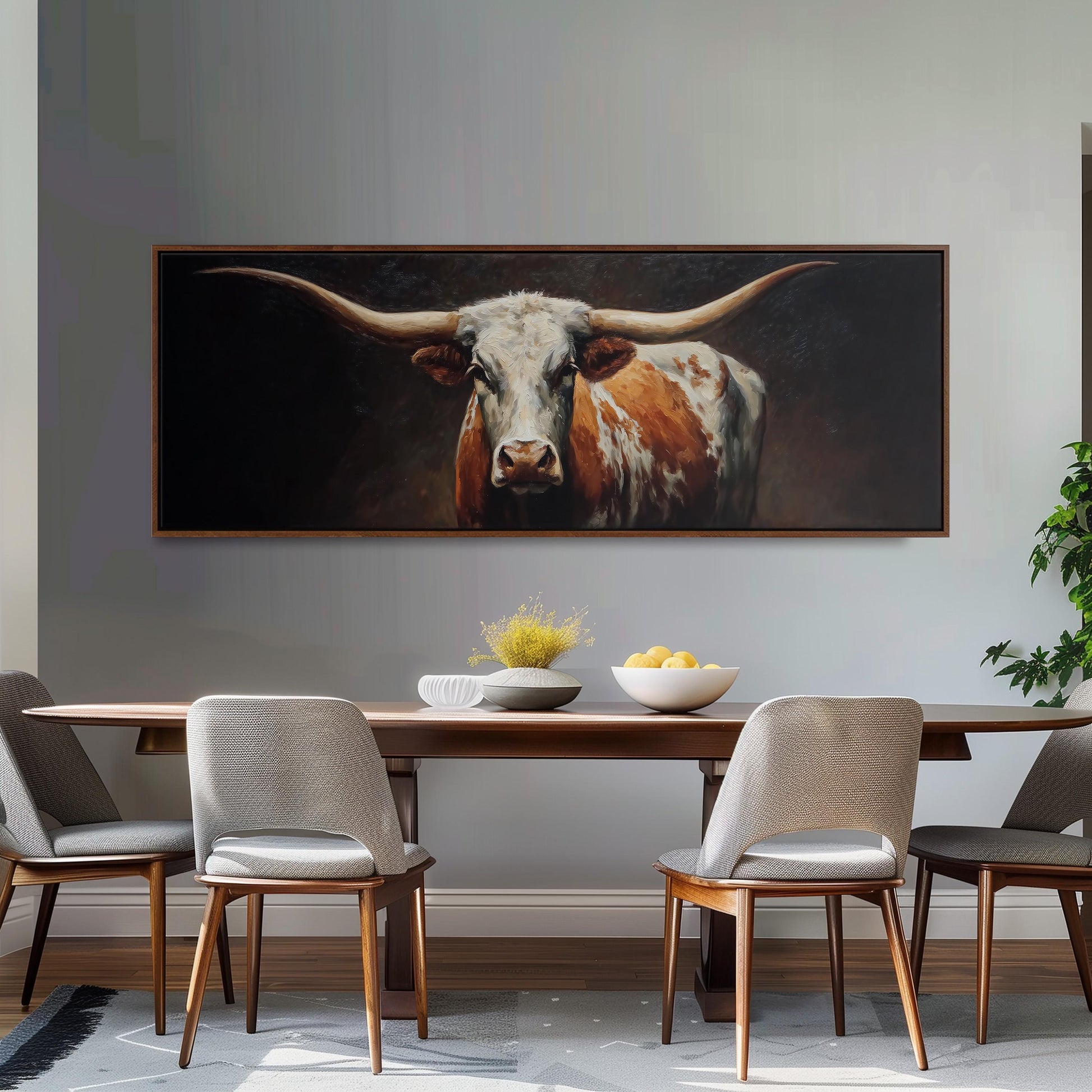 a large painting of a bull with long horns hanging on a wall above a wooden dining table with four chairs.