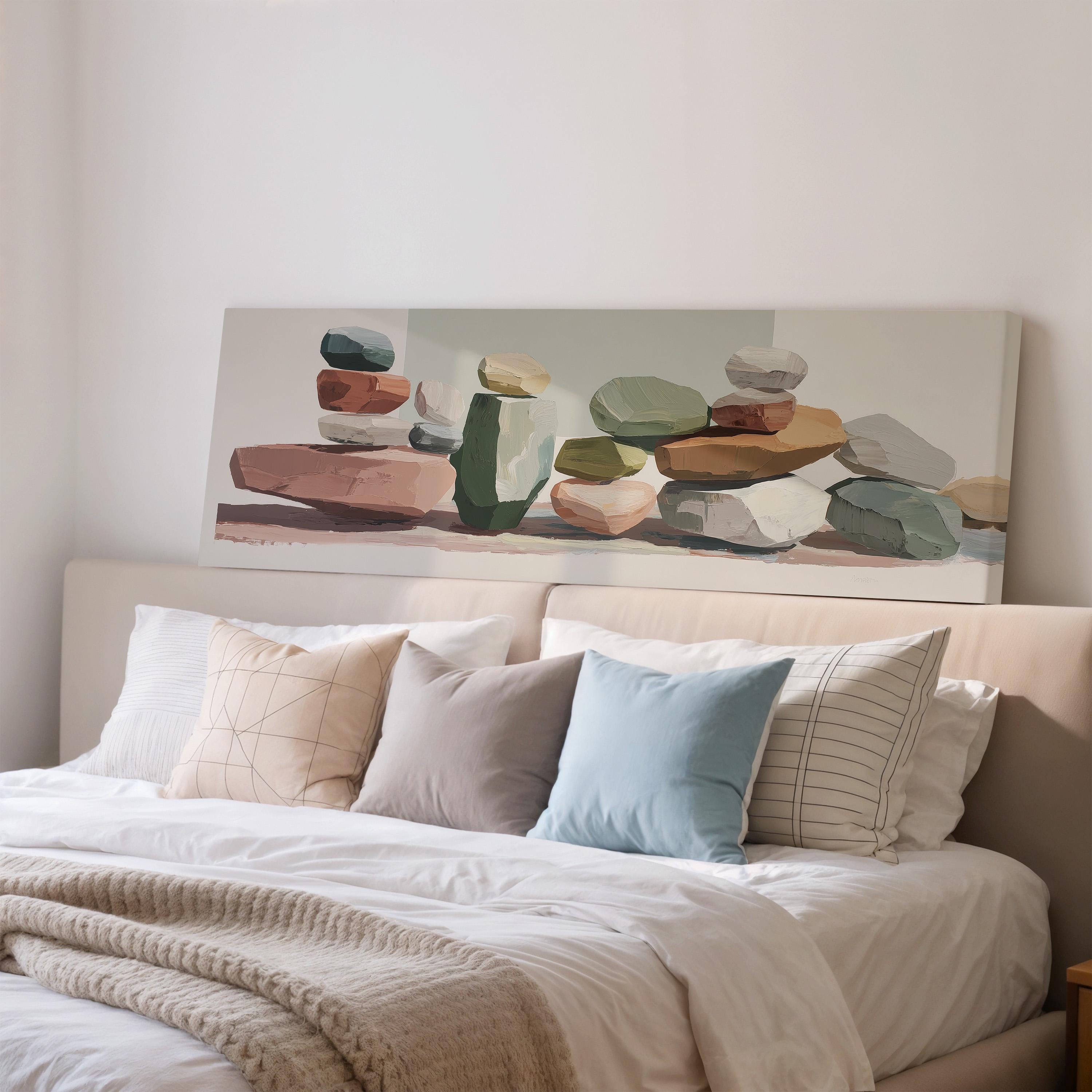 a bedroom with a large bed adorned with various pillows and a blanket. Above the bed, there is a painting of stacked rocks in different colors and sizes.