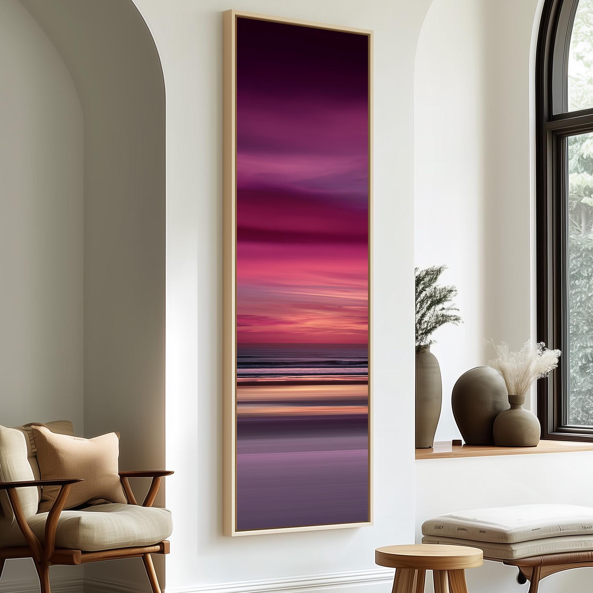 a large, colorful painting of a sunset over the ocean, hanging on a white wall in a modern living room setting.