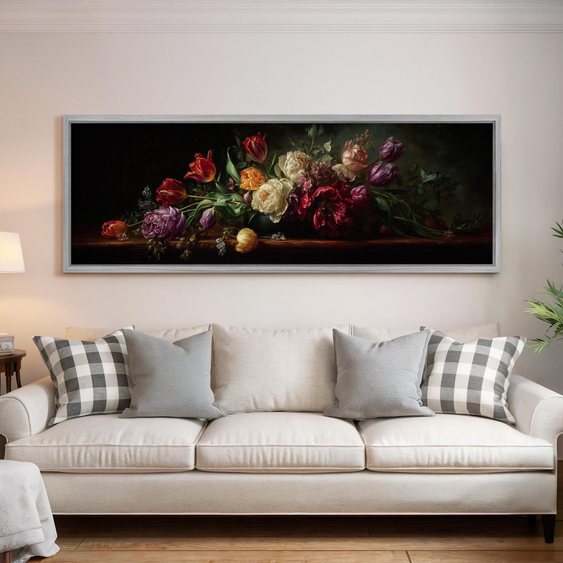 a large painting of a bouquet of flowers hanging on a wall above a white sofa with gray and white patterned pillows.