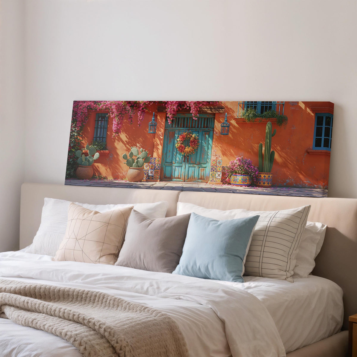 Adobe doorway with a wreath and cacti wide panoramic canvas print above a bed in a bedroom