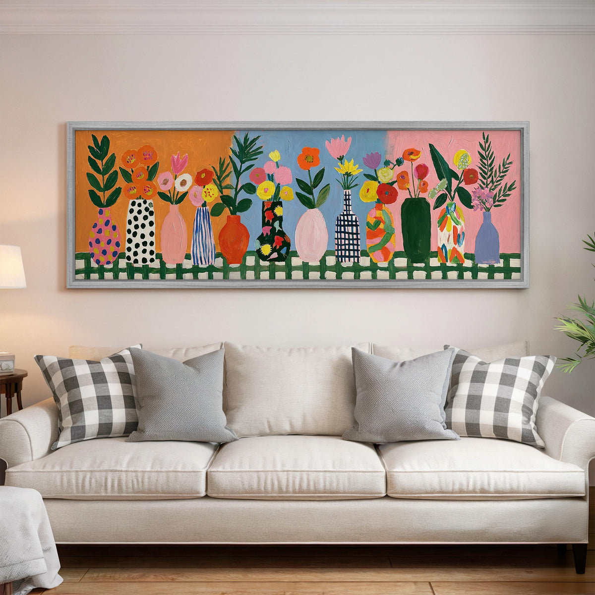 Folk art flower vases on orange and blue panoramic canvas print above a white sofa in a bright living room