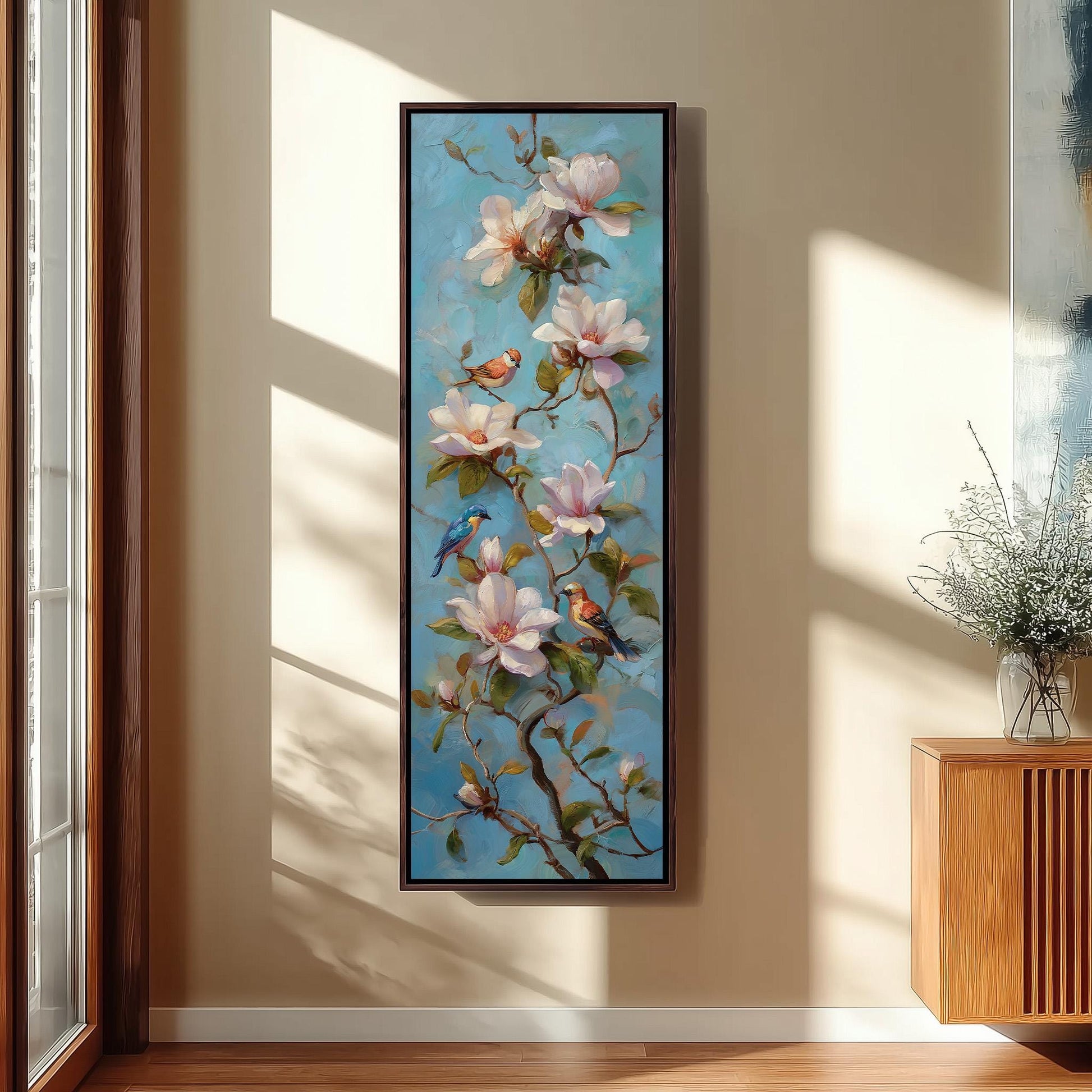a large painting of pink flowers with green leaves and two birds perched on the branches, hanging on a wall in a room with a wooden cabinet and a vase of flowers.
