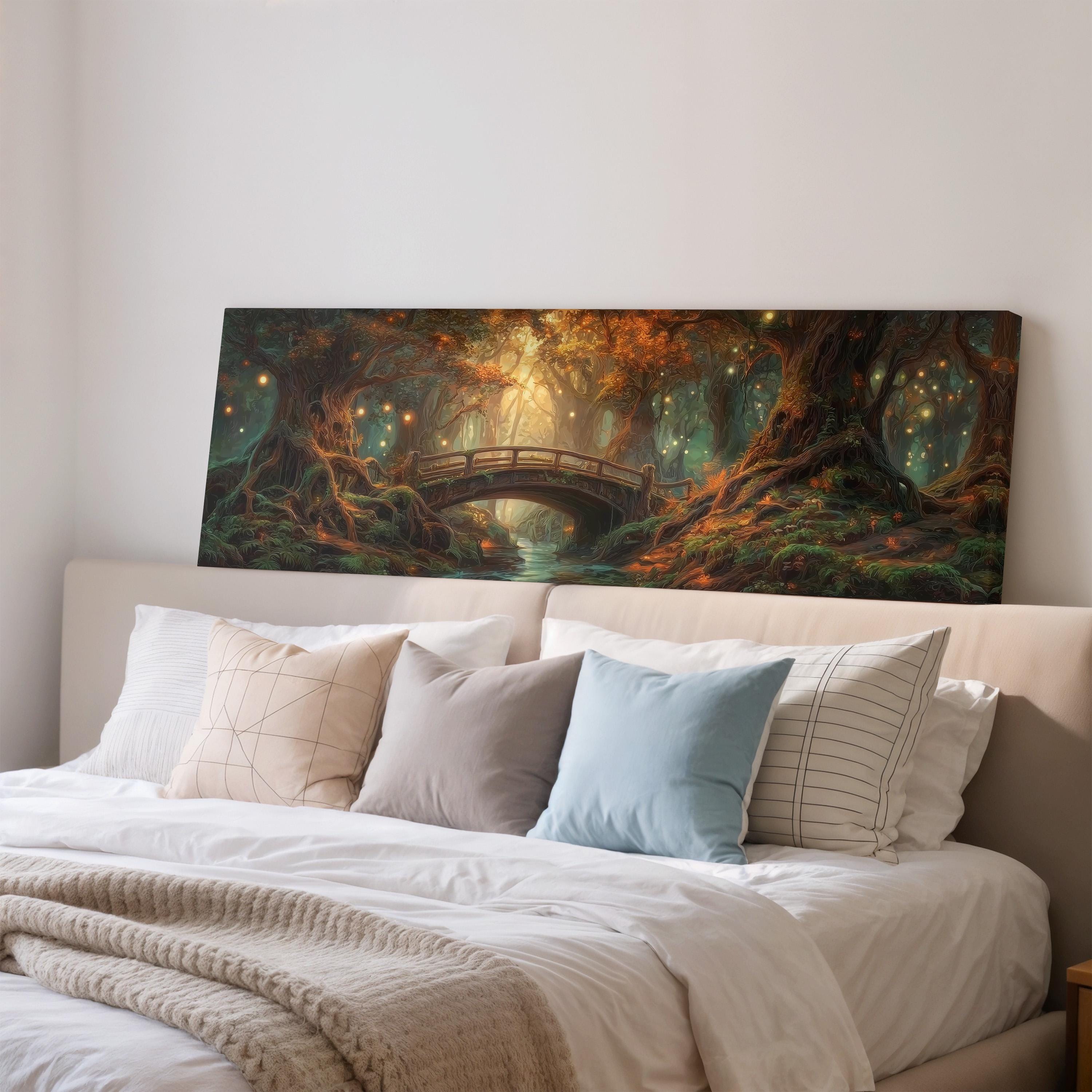 a large painting of a forest scene with a bridge over a river, hanging on a wall above a bed with white pillows and a gray blanket.