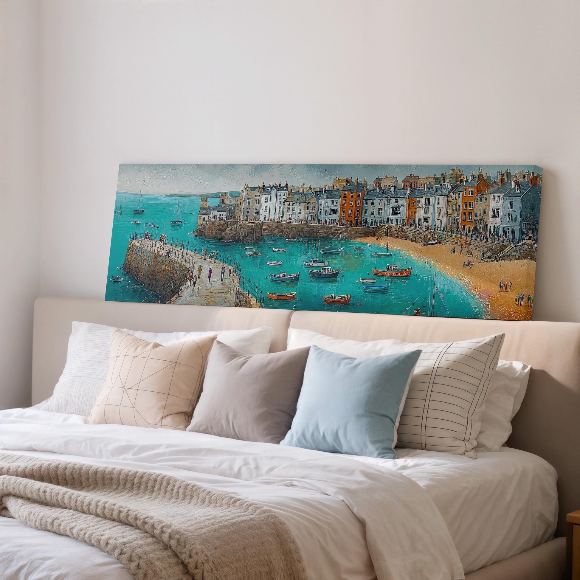 a large painting of a coastal town with boats on the water, hanging on a wall above a bed with white pillows and a gray blanket.