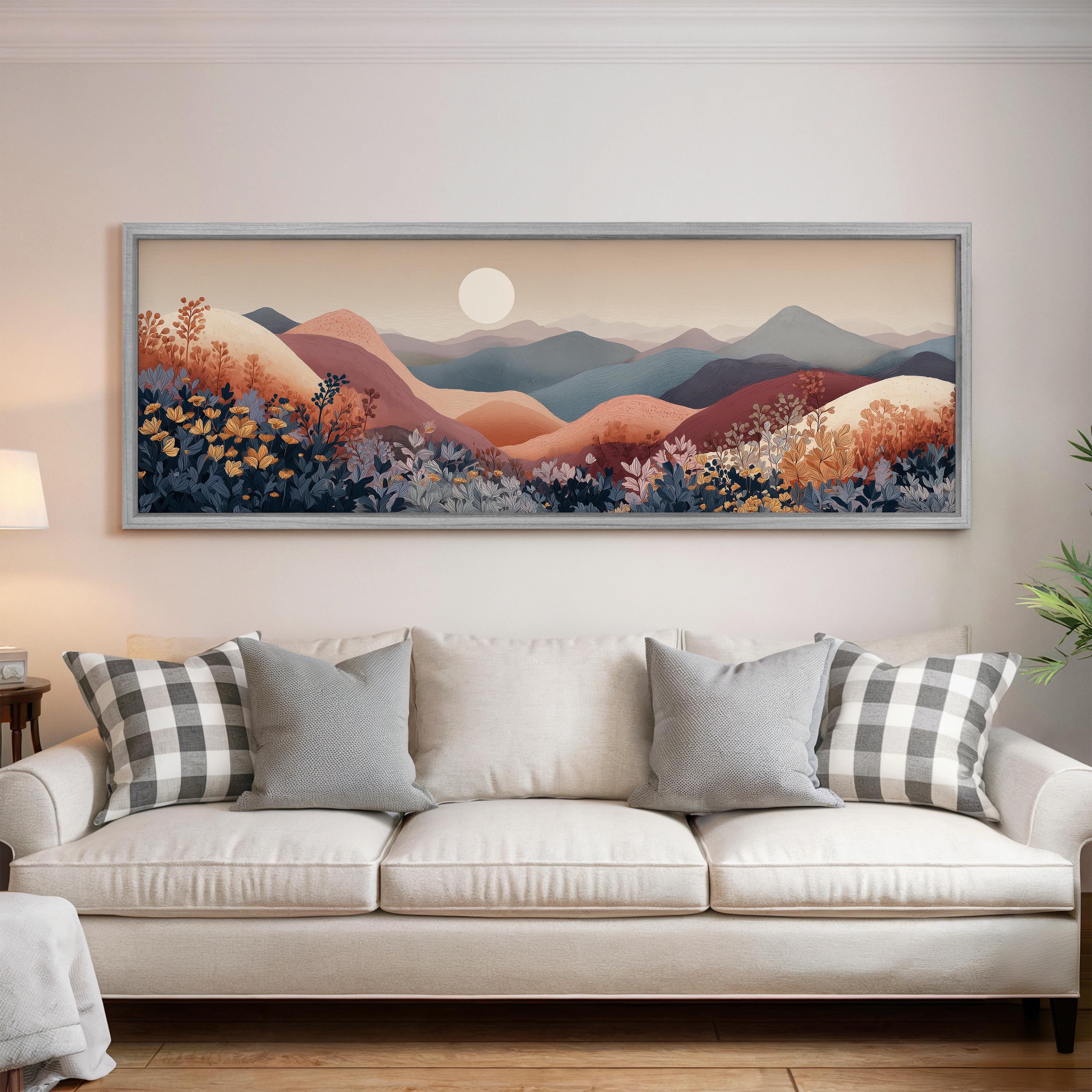 a large, framed landscape painting hanging on a wall above a white sofa with decorative pillows.