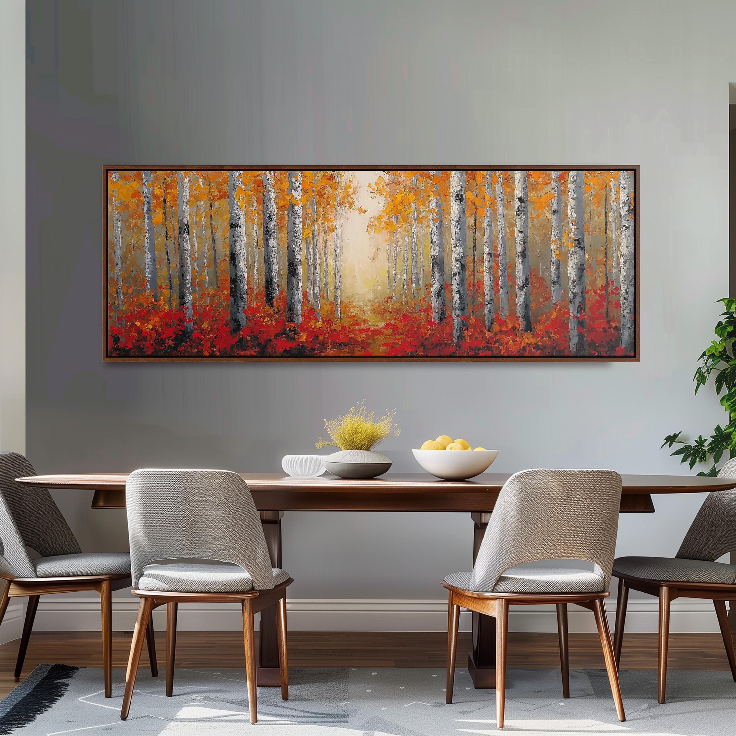 a dining room with a large painting of a forest scene hanging on the wall above a wooden dining table with four chairs. The painting depicts a path leading through a forest of trees with vibrant orange and red foliage.