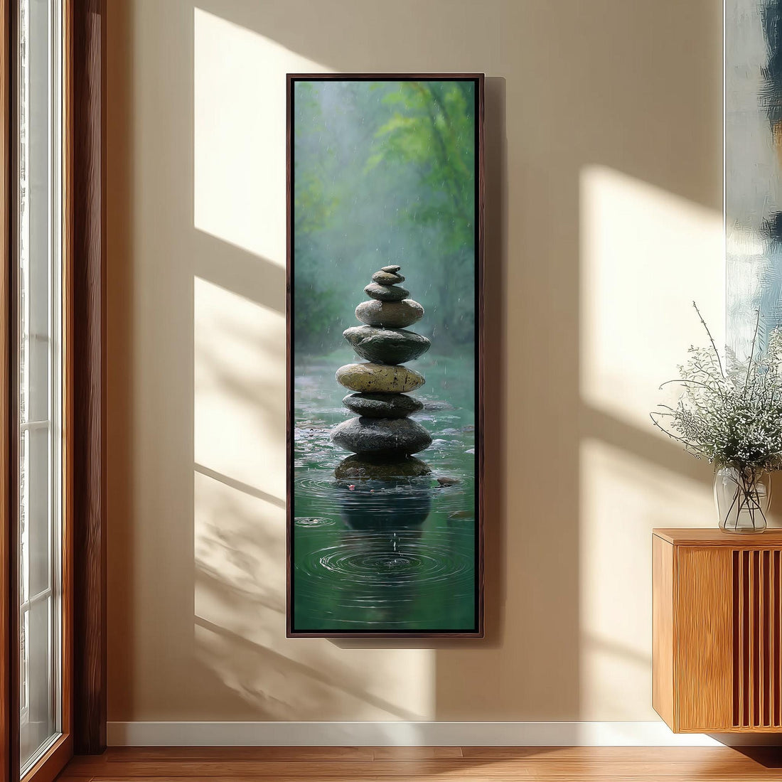a large framed painting of a stack of stones in a tranquil, natural setting, with water below creating a reflective surface.