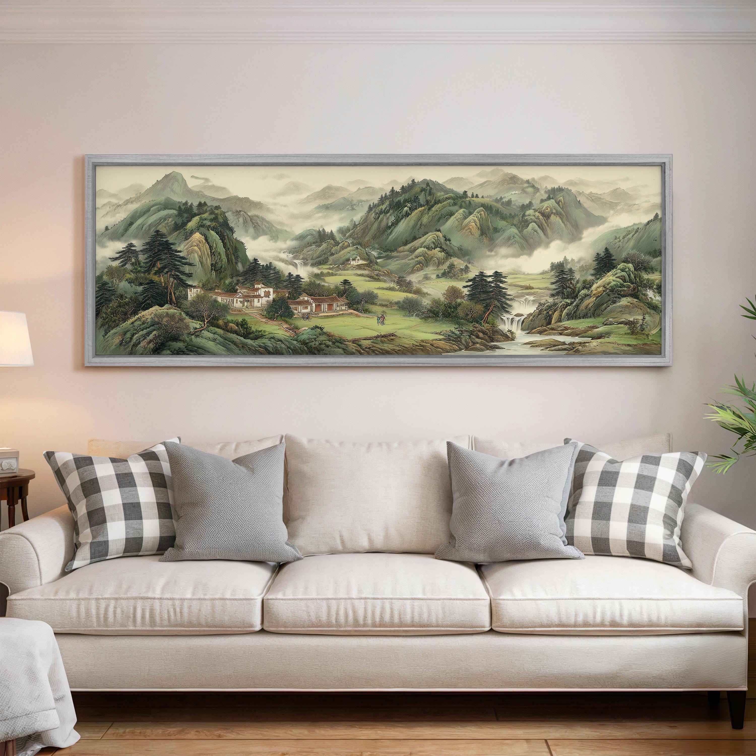 a large landscape painting hanging on a wall above a white sofa with gray and white patterned pillows.