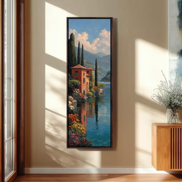 a large framed painting of a picturesque landscape with a red building, a river, and mountains in the background.