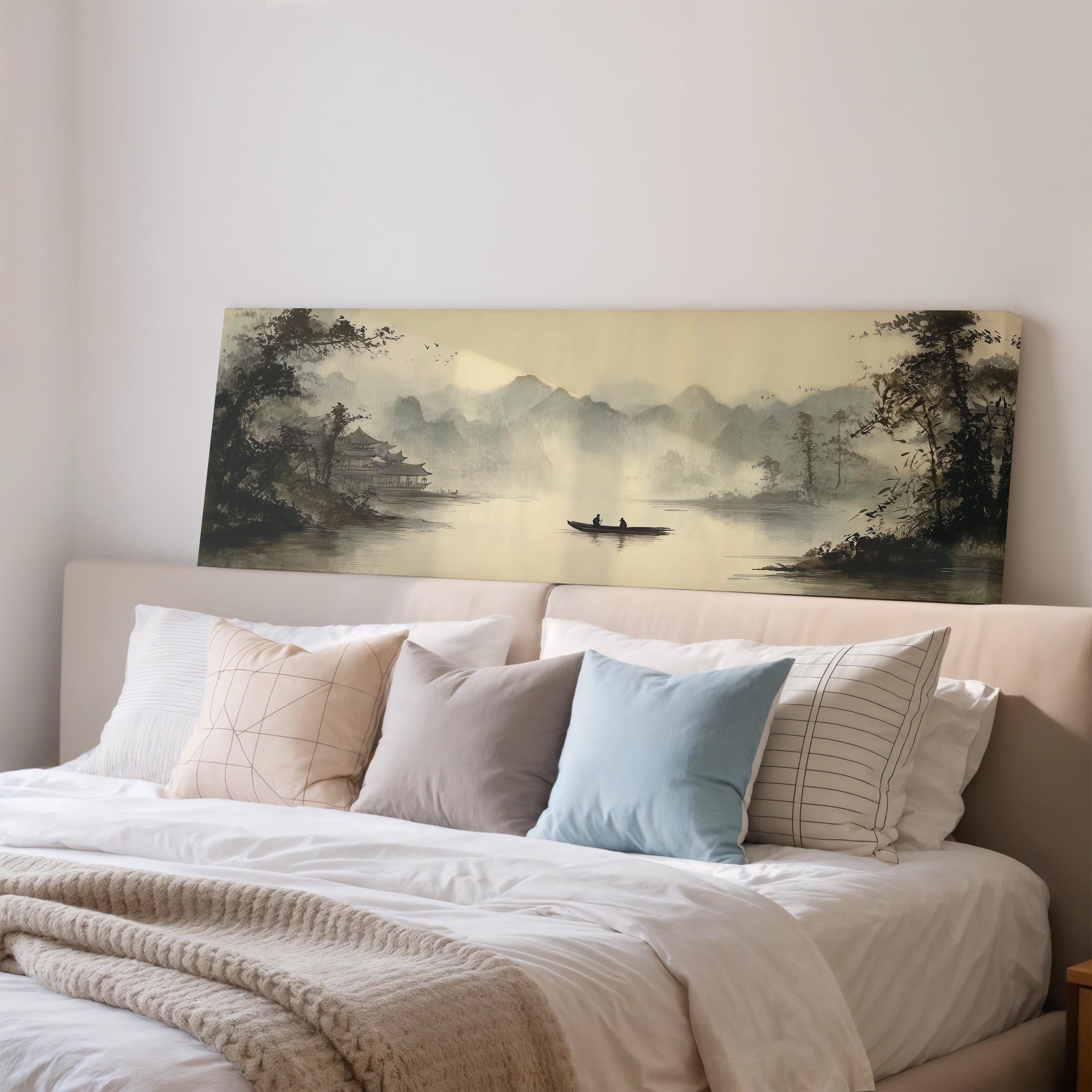 a large painting of a serene landscape with a boat on a lake, hanging above a bed with white pillows and a gray blanket.