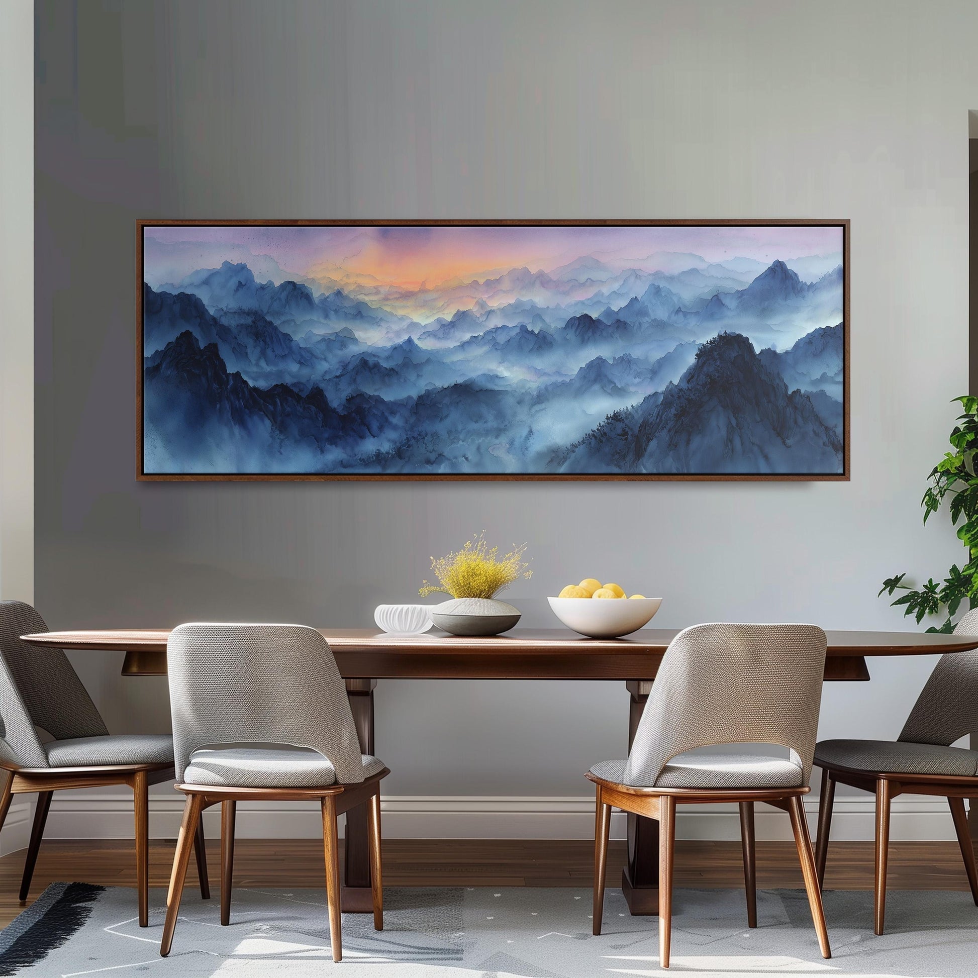 a dining room with a large painting of a mountainous landscape hanging on the wall above a wooden dining table with four chairs. The table is set with a bowl of fruit and a vase of flowers, creating a cozy and inviting atmosphere.