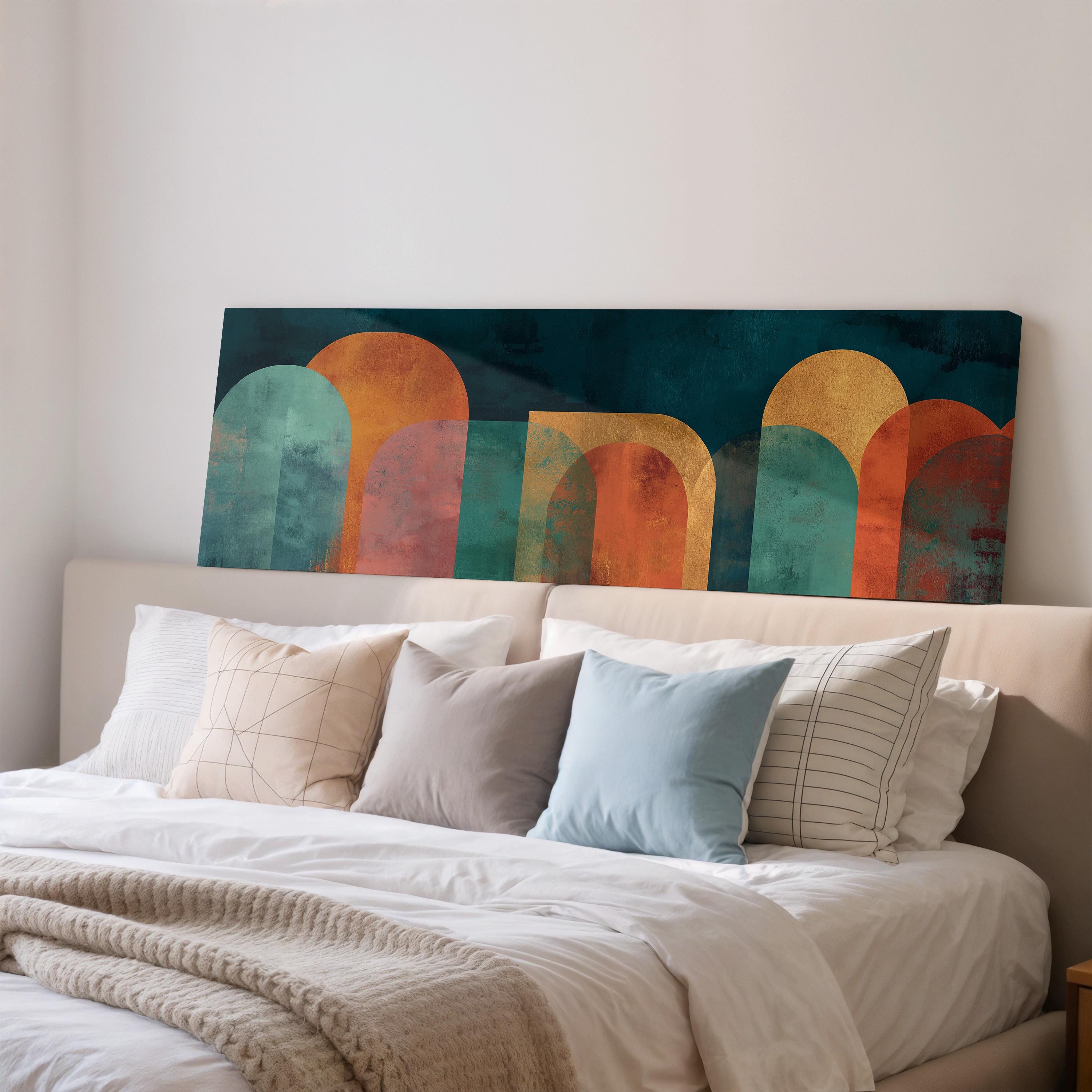 a modern bedroom with a large bed adorned with white pillows and a blue throw blanket. Above the bed, there is a large abstract painting in shades of blue, orange, and green.