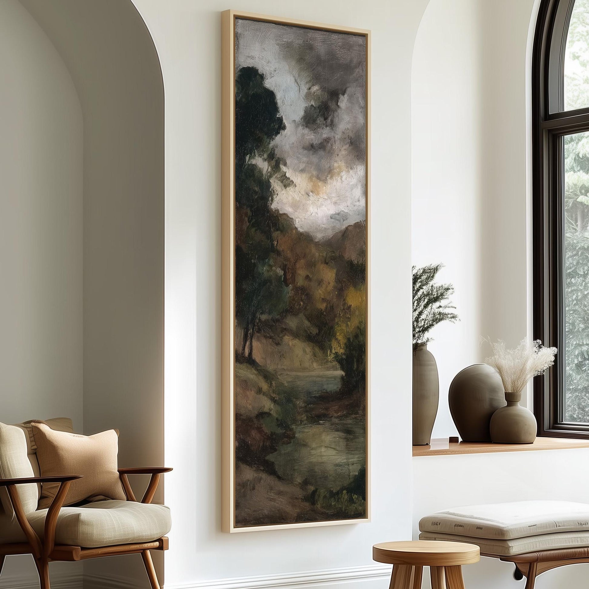 a large painting of a landscape hanging on a wall, with a window and two chairs in the foreground.