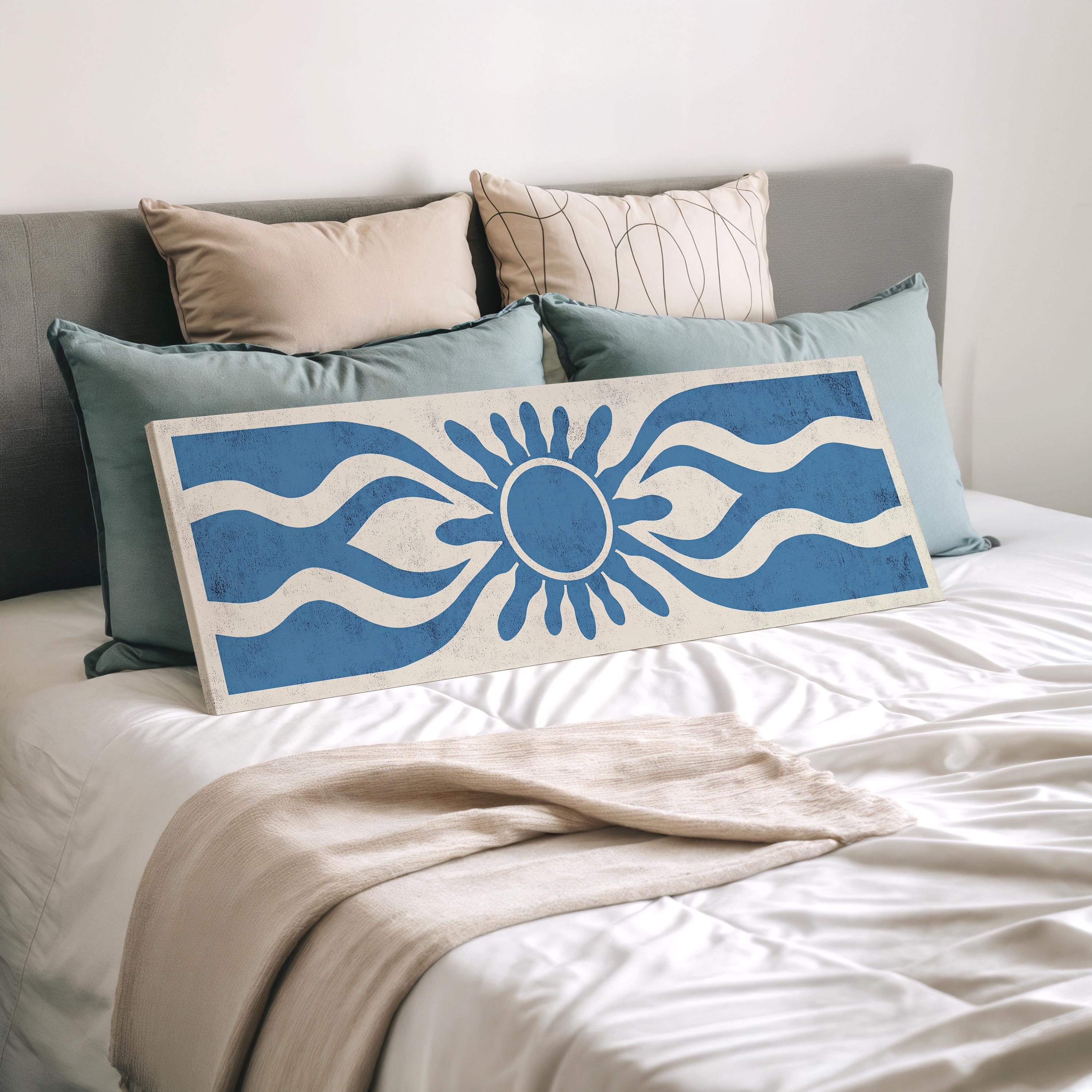 a bed with a white comforter and a blue and white patterned pillow. There is also a large rectangular canvas or painting with a blue and white design on it, placed on the bed.