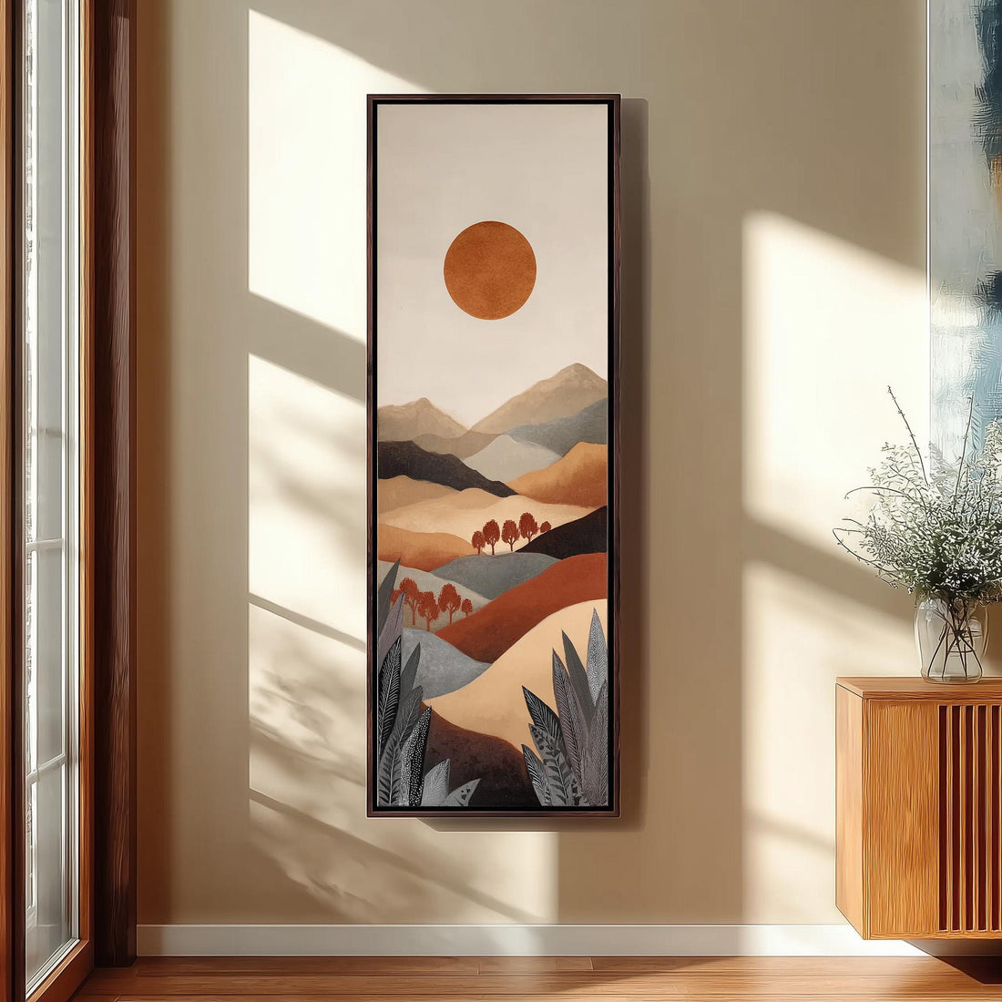 a large, colorful painting of a landscape with mountains and a sun in the background, hanging on a wall in a room with a window and seating area.