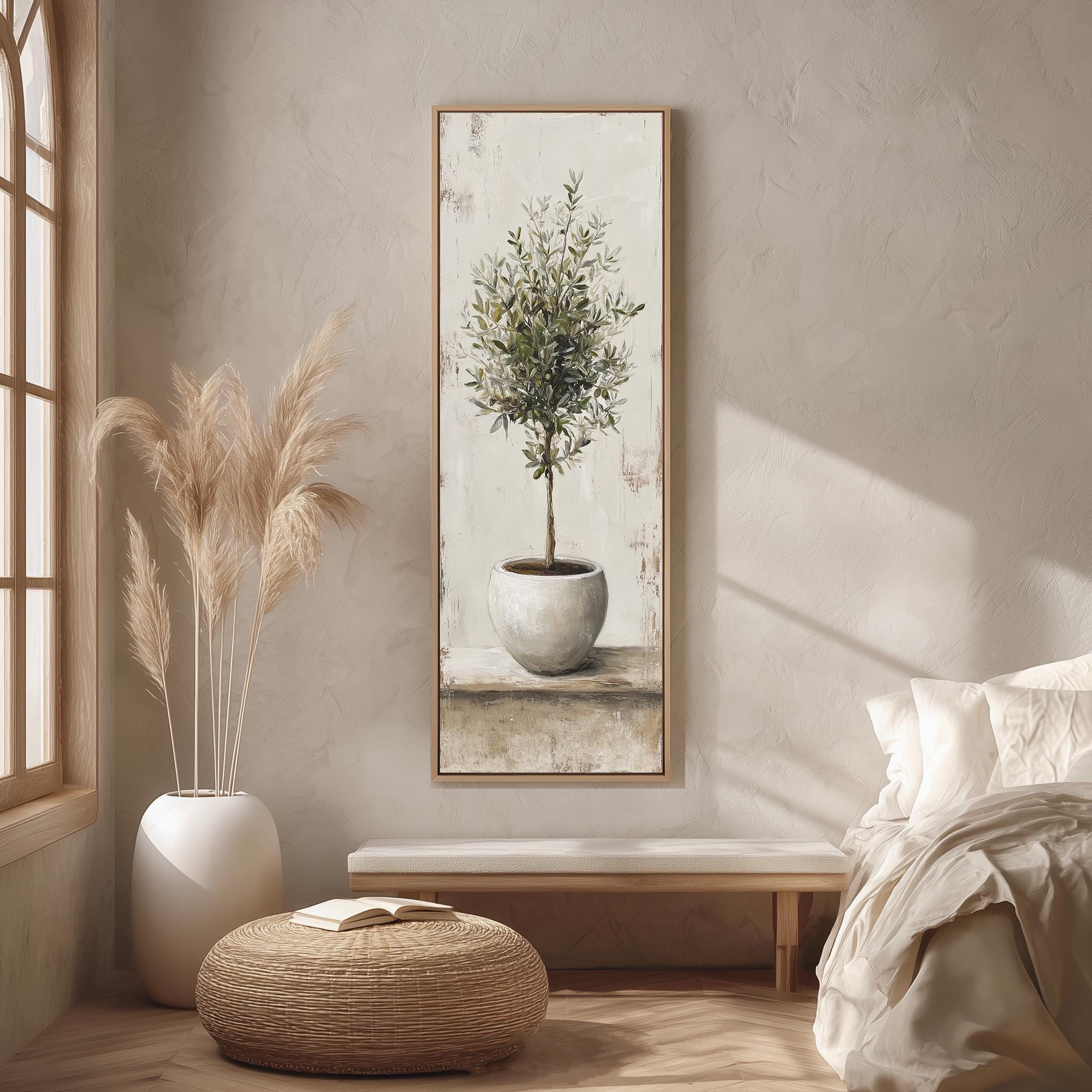 a serene and cozy bedroom scene, featuring a large painting of a potted olive tree hanging on the wall, a white vase with tall pampas grasses, a wooden bench, and a woven ottoman.