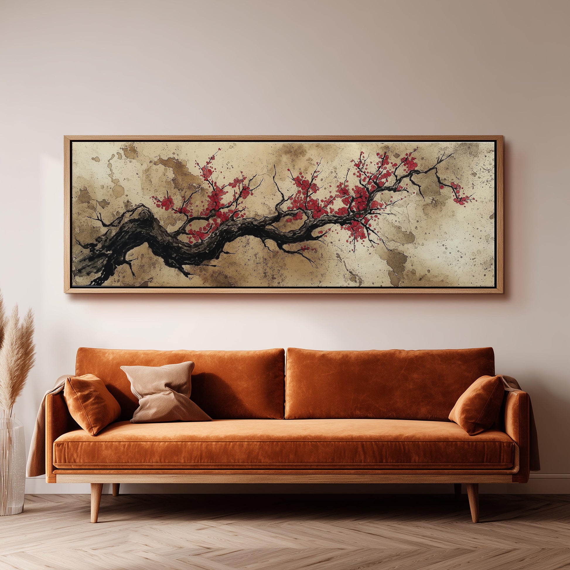 a large, framed painting of a tree branch with red flowers hanging above a brown sofa in a living room setting.
