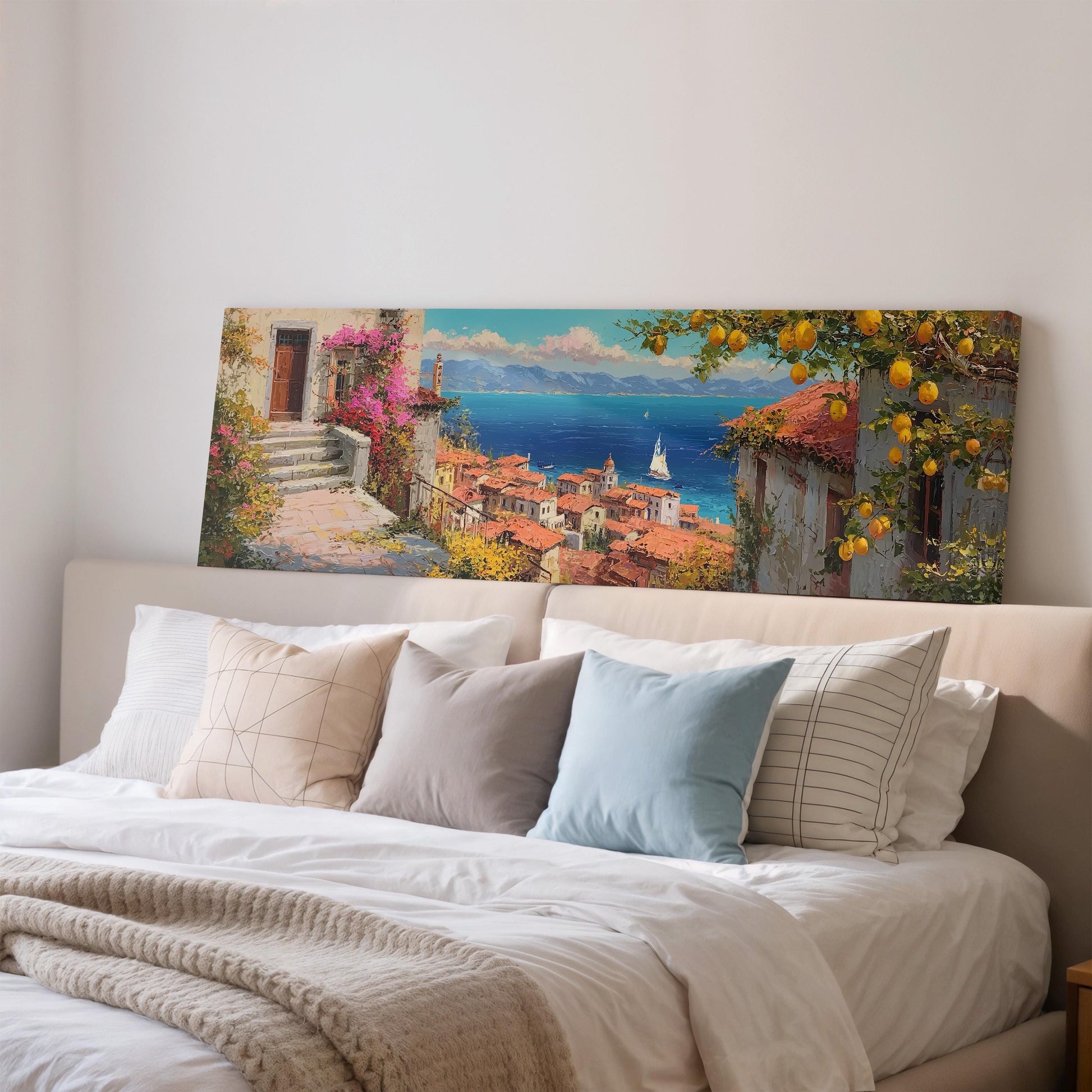 a large painting of a coastal town with a ship in the distance, hanging above a bed with white pillows and a gray blanket.