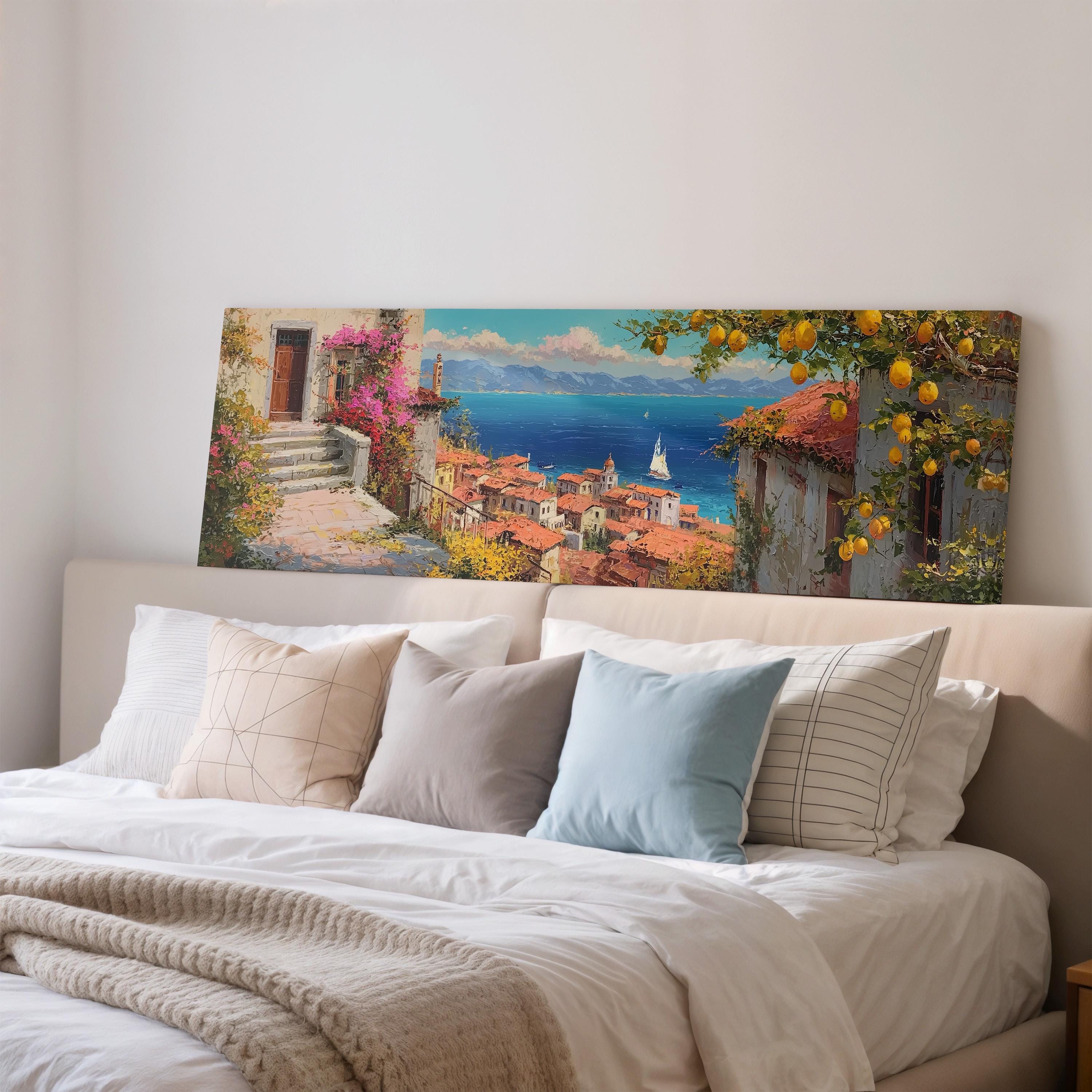 a large painting of a coastal town with a ship in the distance, hanging above a bed with white pillows and a gray blanket.