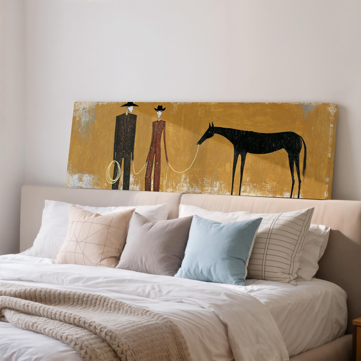 Two cowboys with a dark horse on gold wide panoramic canvas print above a bed in a bedroom