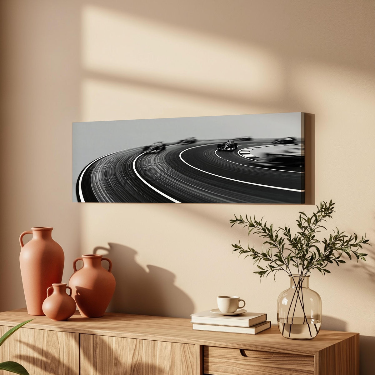 Race cars sweeping around a curve in black and white long horizontal canvas print above a wooden sideboard