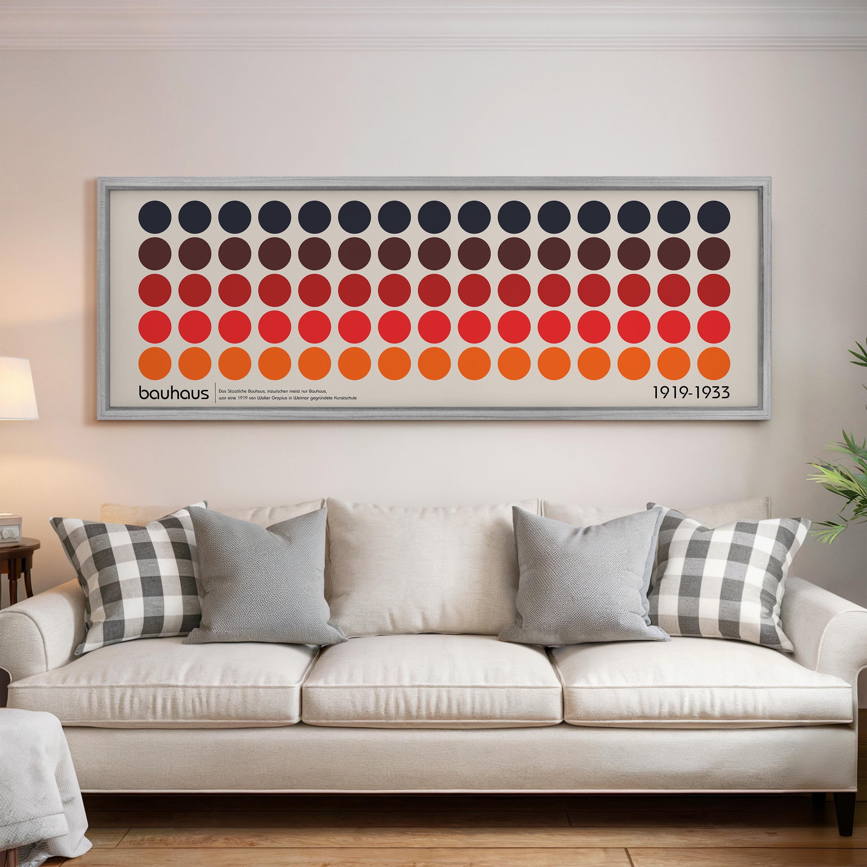 a large framed poster of a repeating pattern of circles in various colors, hanging on a wall above a white couch with patterned throw pillows.