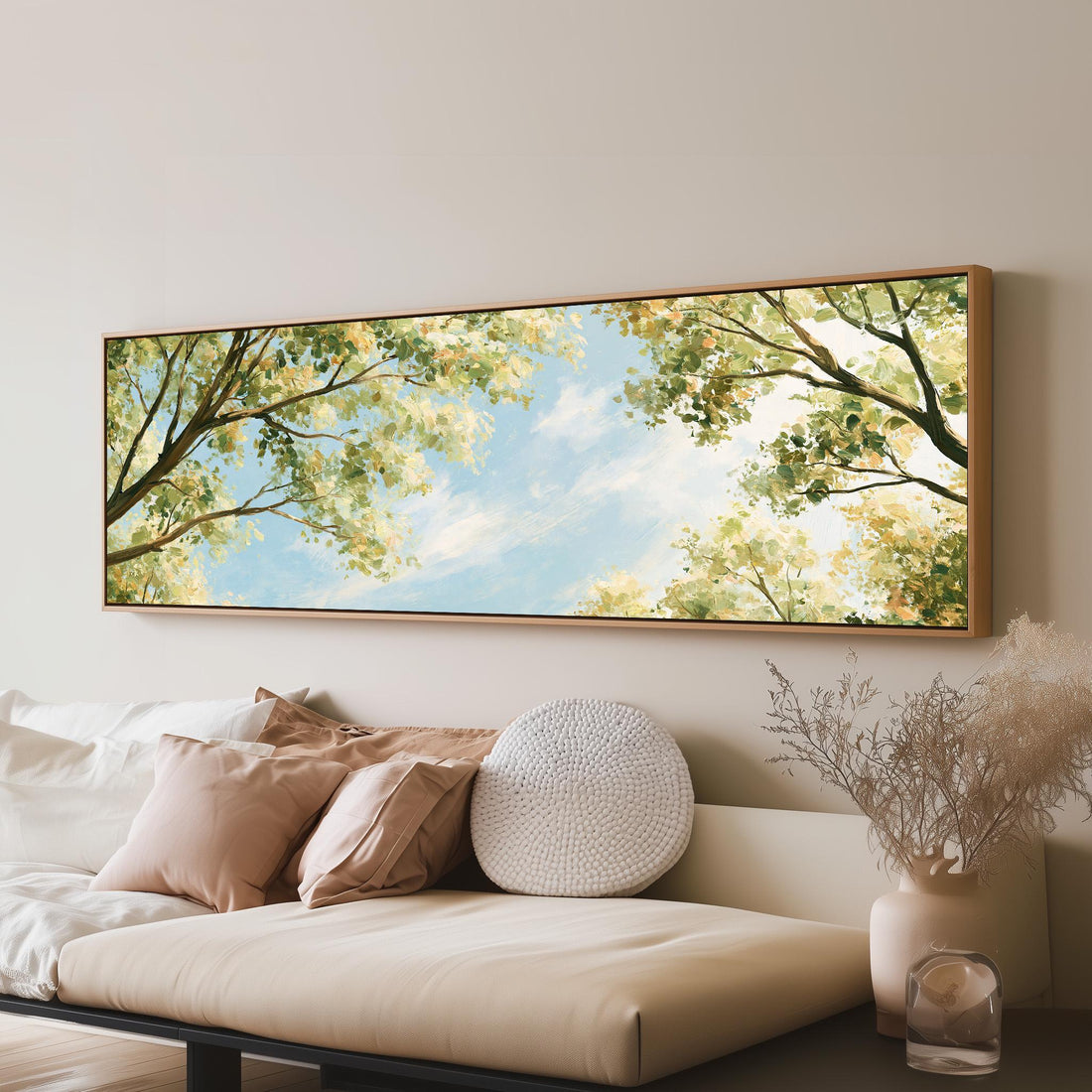 Sunlit leafy branches framing soft clouds long horizontal canvas print above a sofa in a living room