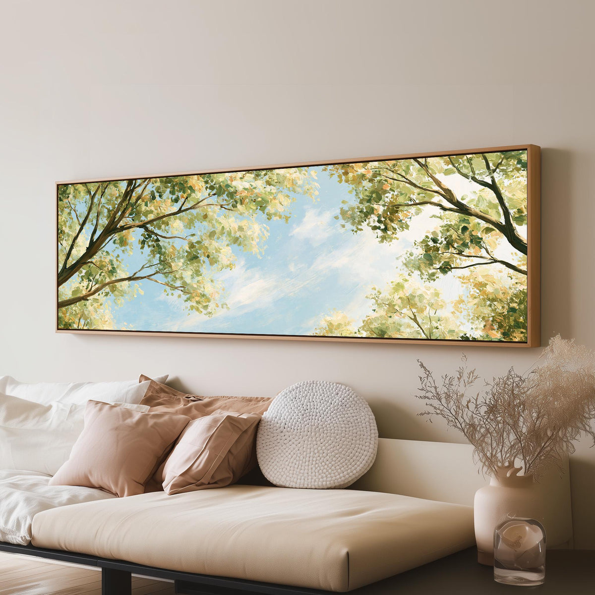 Sunlit leafy branches framing soft clouds long horizontal canvas print above a sofa in a living room