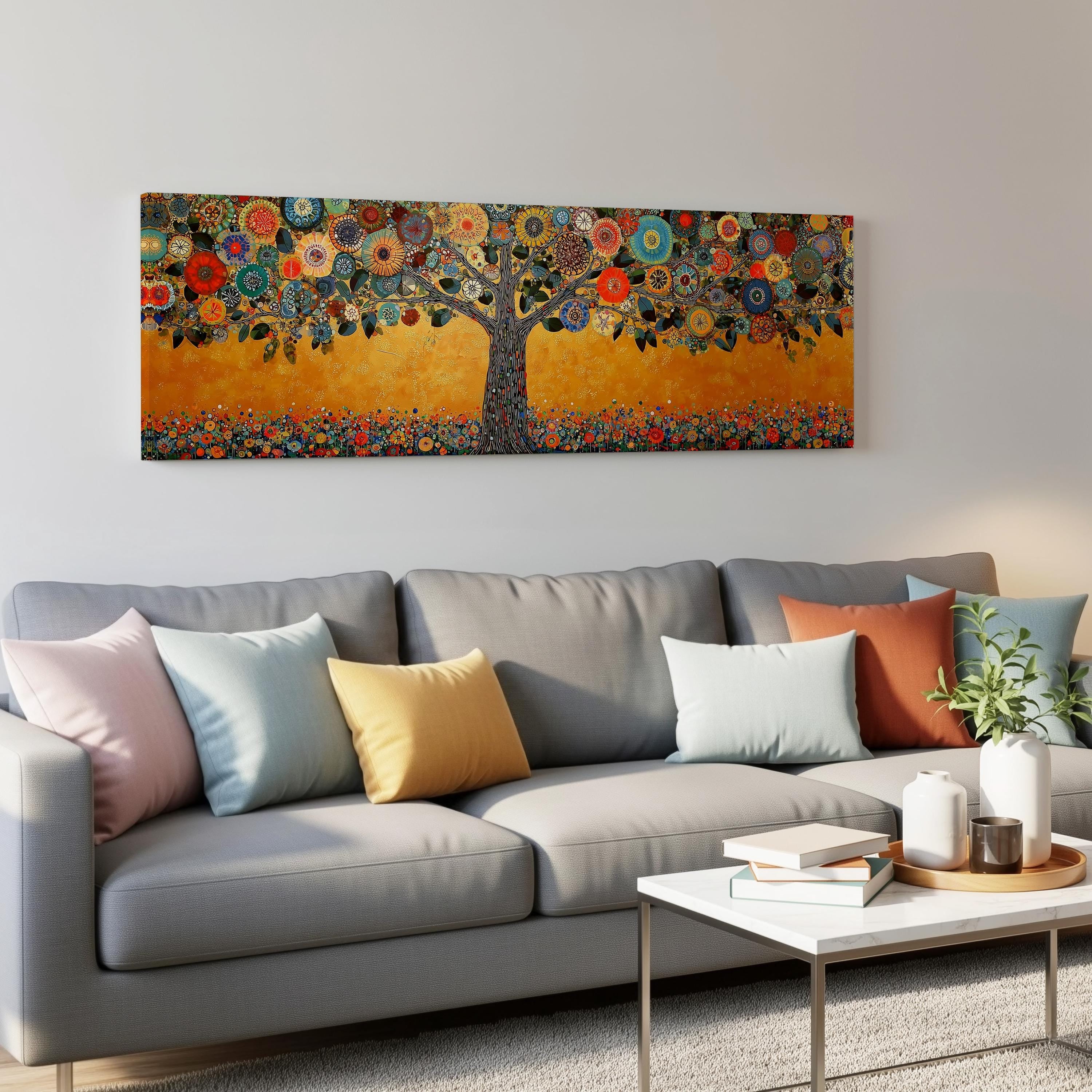 a large, colorful painting of a tree hanging on a wall above a gray couch with various throw pillows. The couch is positioned in front of a coffee table with books and a plant on it.