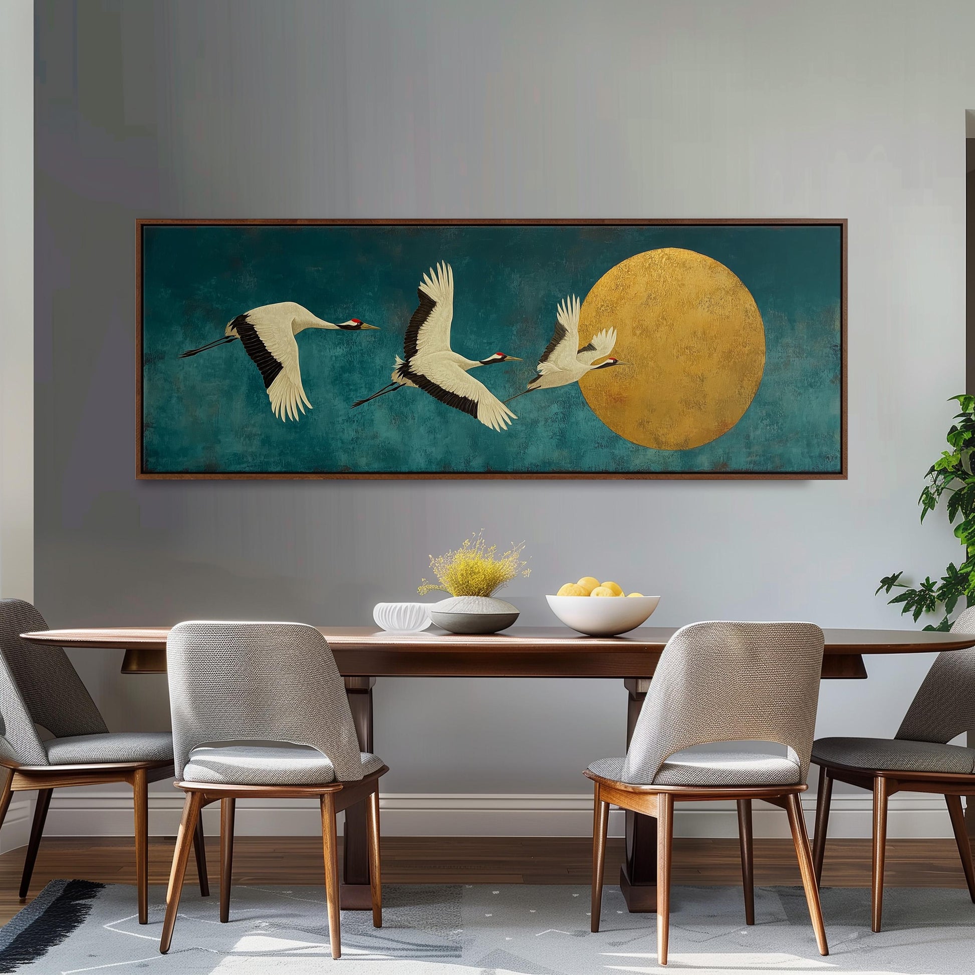 a large painting of three white birds in flight against a blue background, with a large yellow circle in the center. The painting is hanging on a wall above a wooden dining table with four chairs around it.