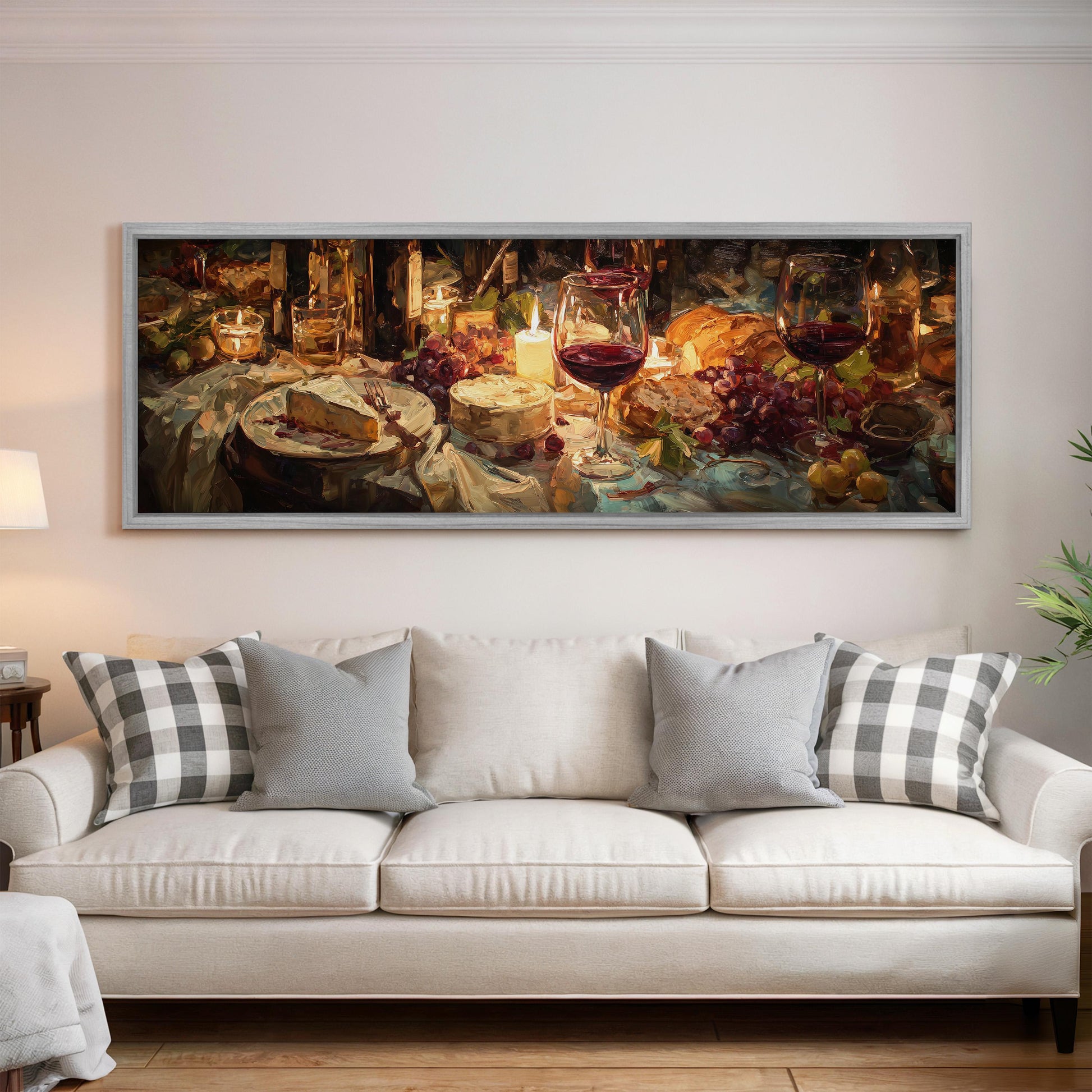 a large painting of a table with various food items, including wine glasses, a cake, and grapes, hanging on a wall above a white couch.