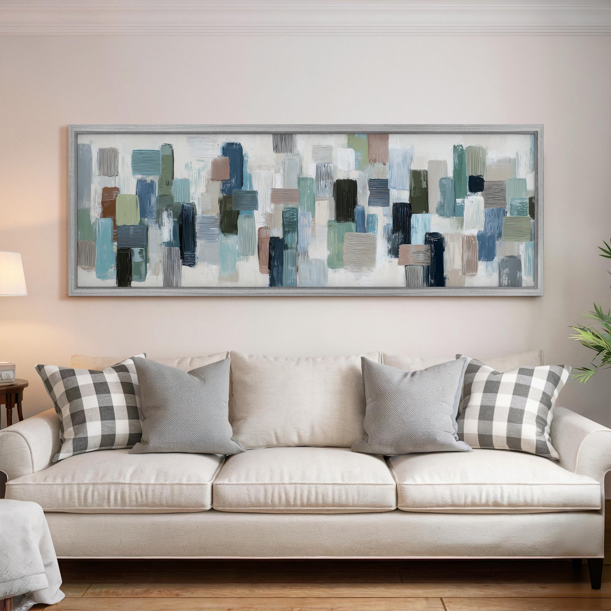 a large, abstract painting hanging on a wall above a white couch with gray and white pillows.