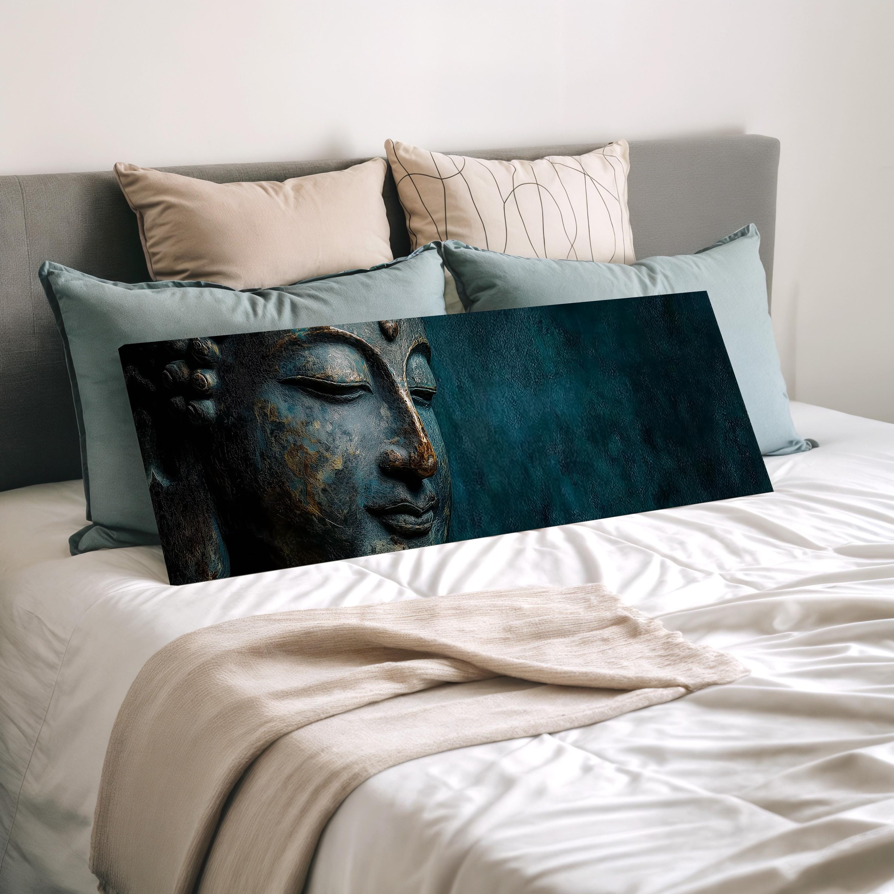 a large bed with a framed picture of a Buddha's face on it, surrounded by various pillows.