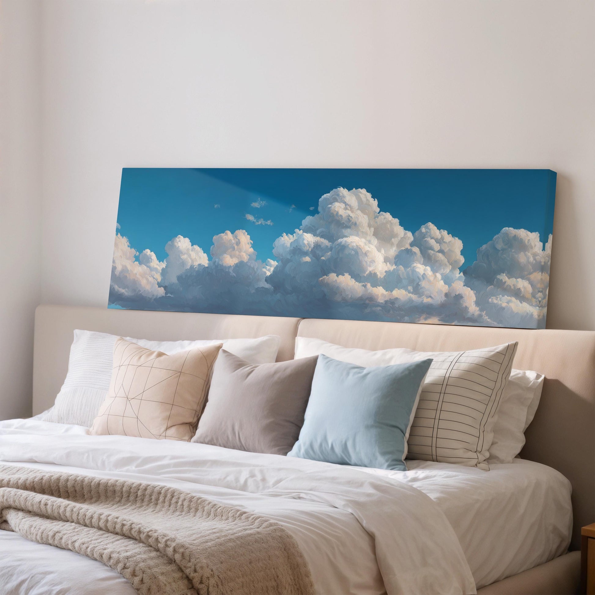 a large bed with white sheets and pillows, and a large canvas print of a blue sky with fluffy white clouds hanging above it.