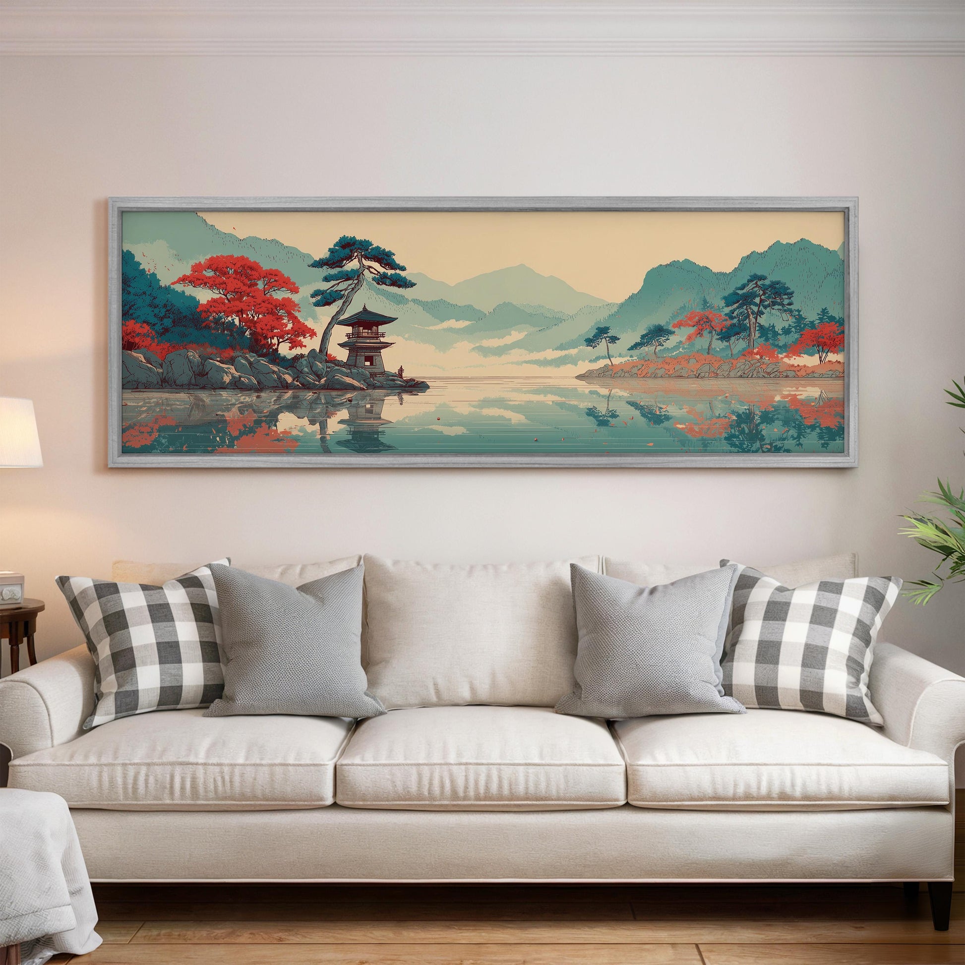 a large, framed painting of a serene landscape with mountains, trees, and a temple, hanging on a wall above a white couch with patterned pillows.