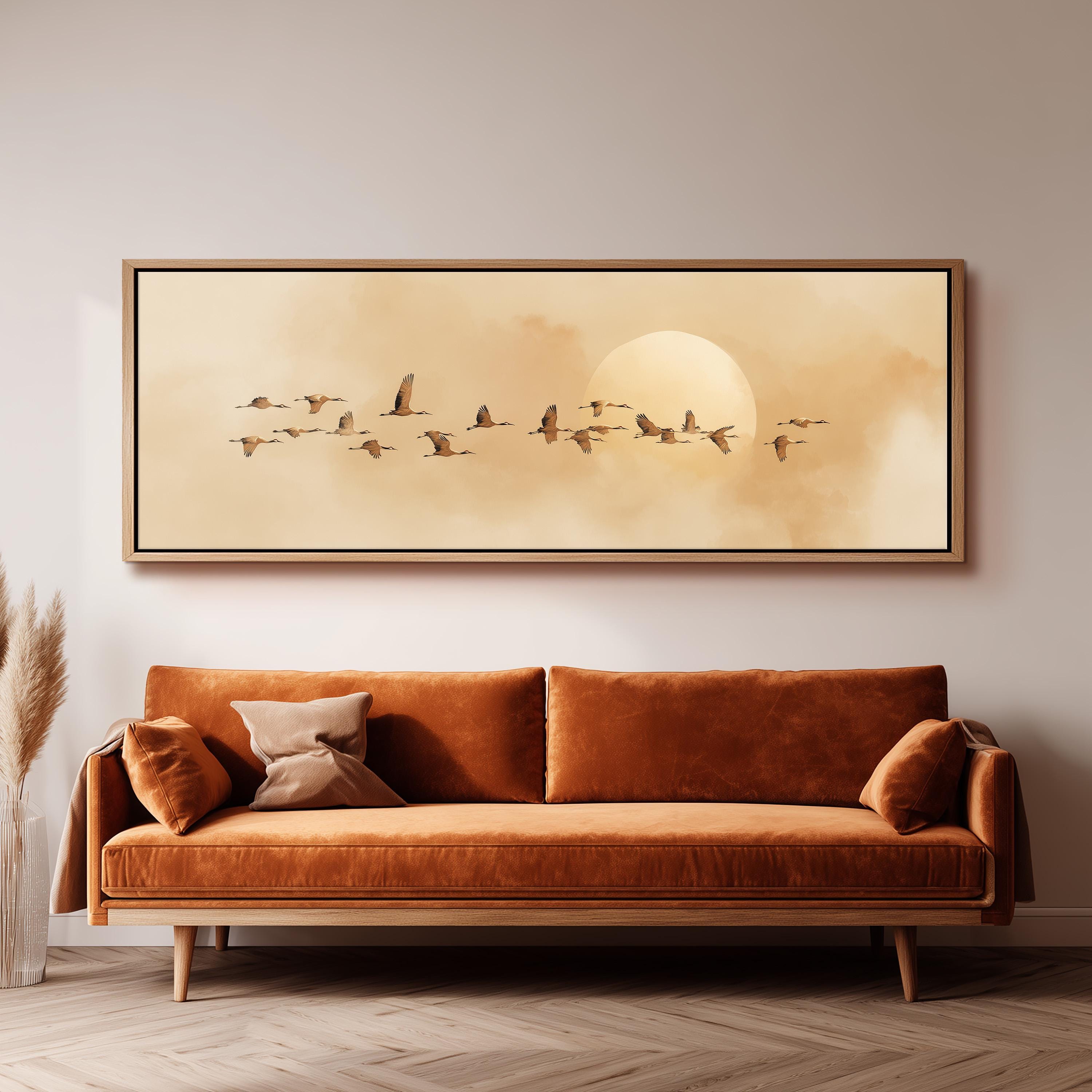 a large, framed painting of a flock of birds flying across a cloudy sky, with a large sun in the background.