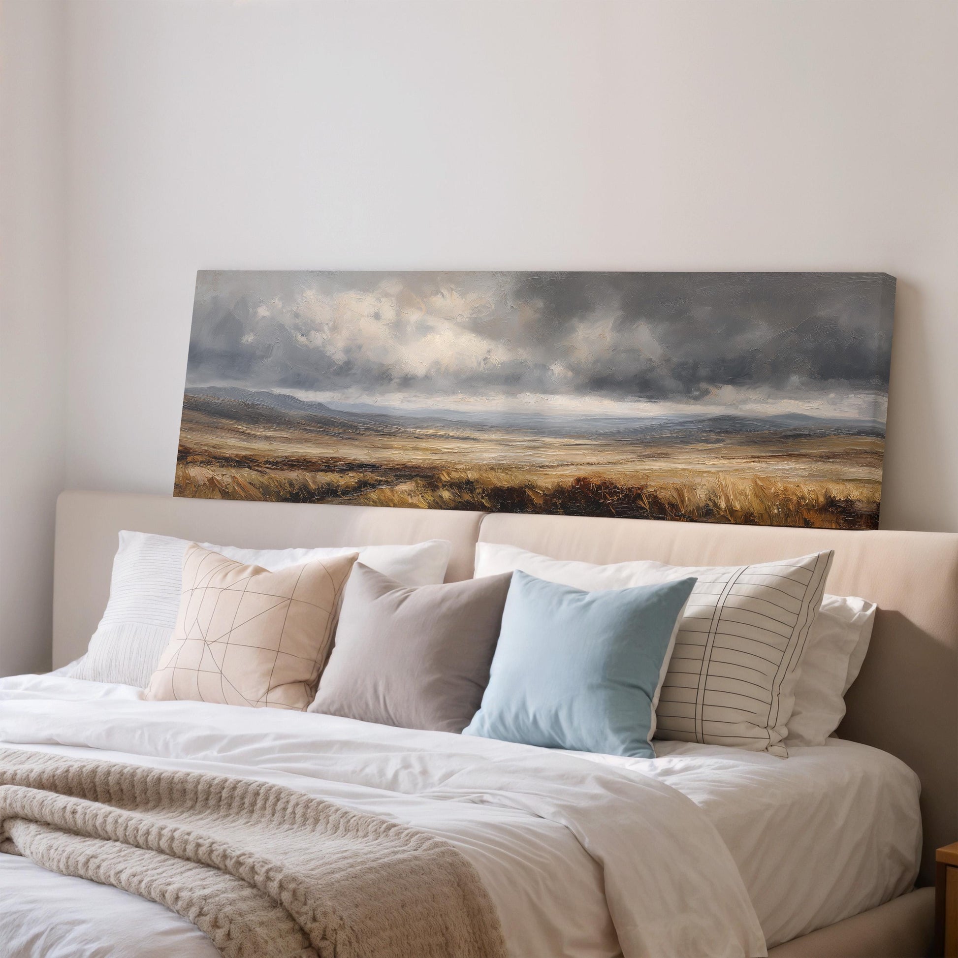 a large landscape painting hanging on a wall above a bed with white bedding and pillows.