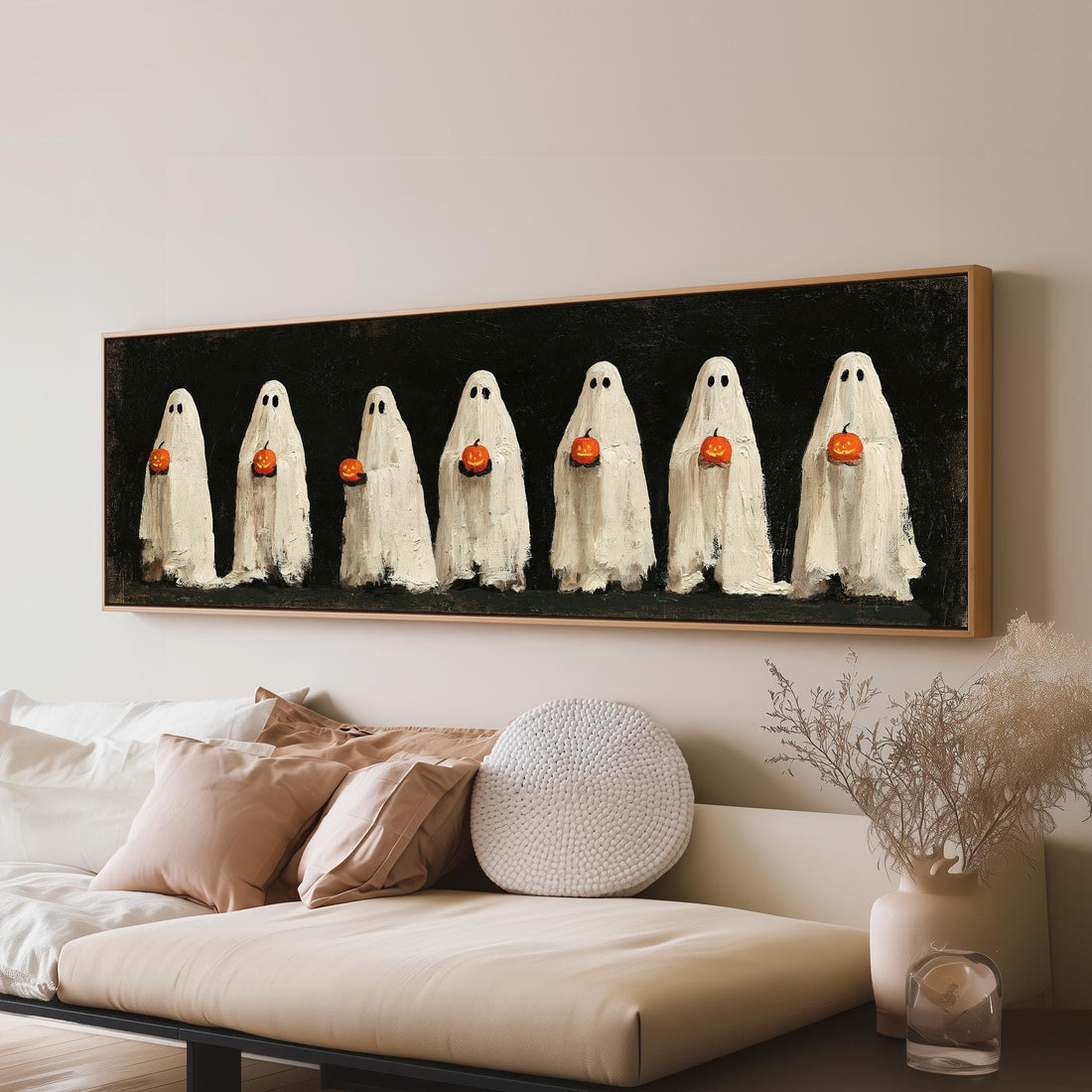 Row of ghosts holding pumpkins long horizontal canvas print above a sofa in a living room