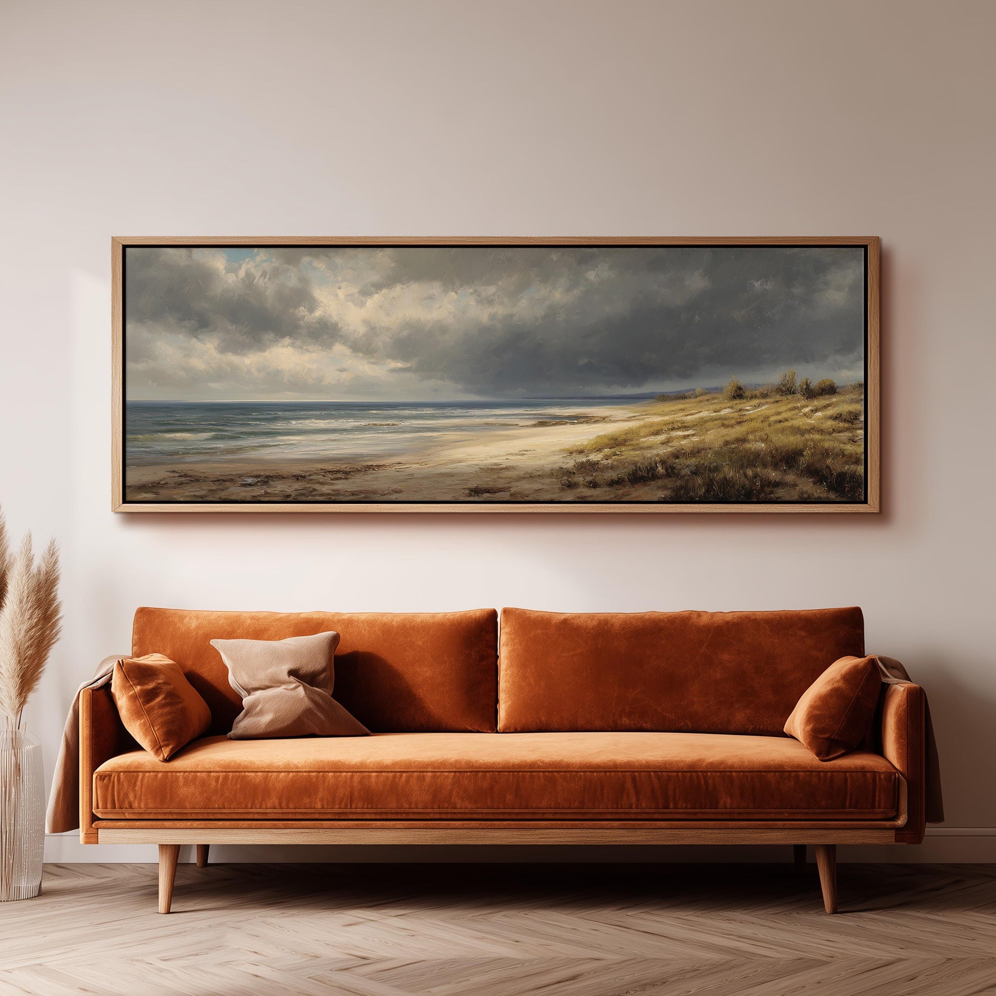 a large, framed painting of a beach scene hanging on a wall above a brown sofa.